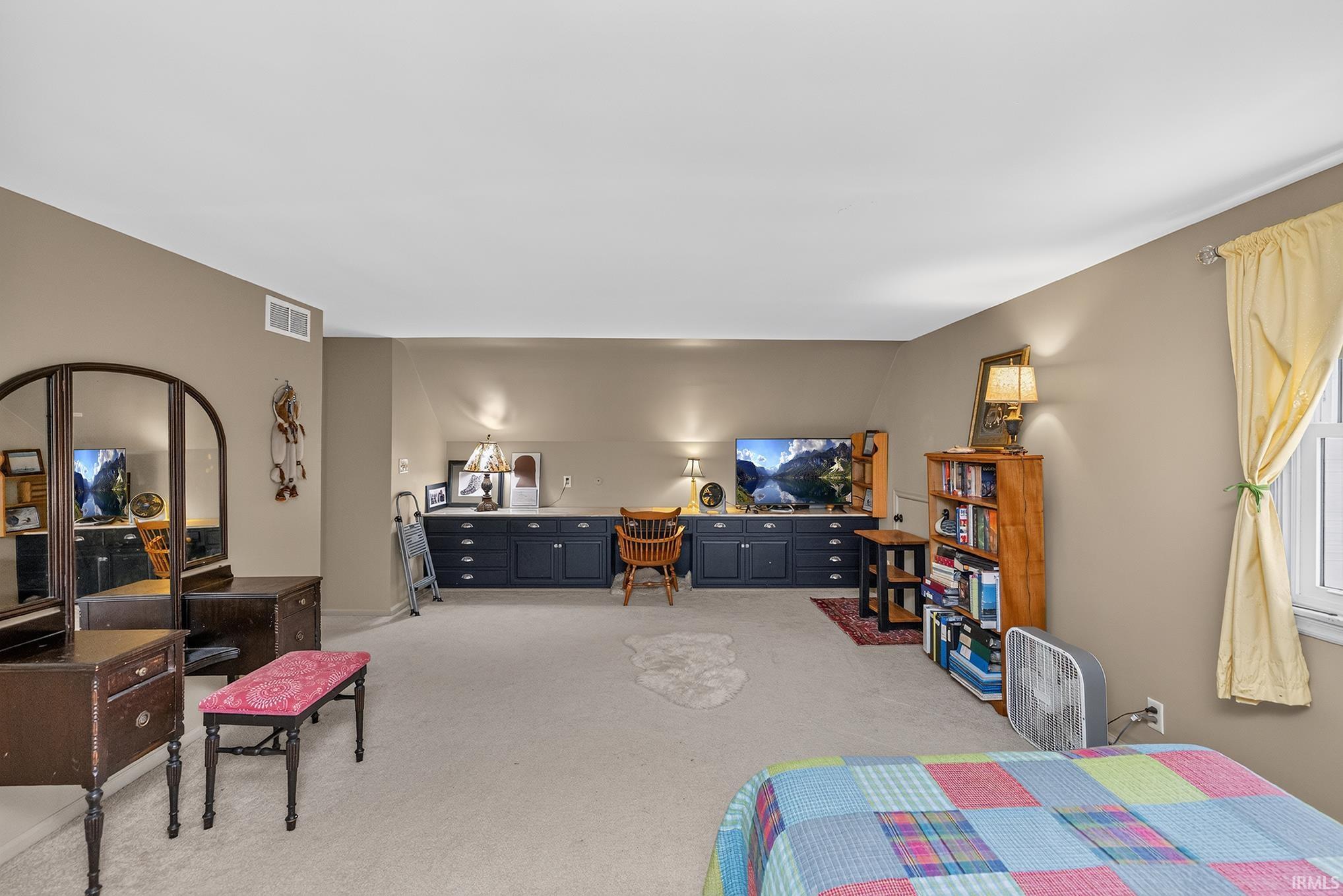 Spacious room featuring neutral-toned walls and light-colored carpeting