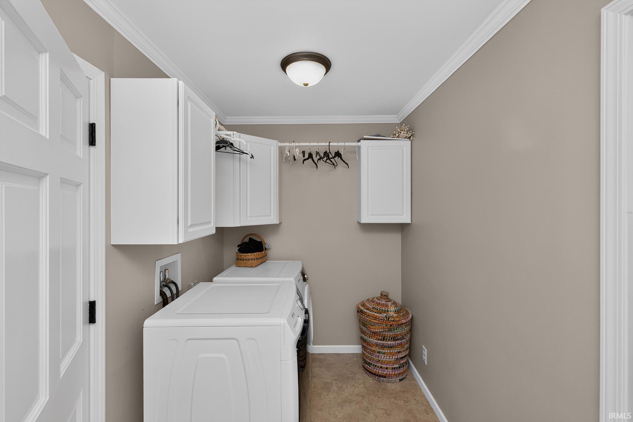 Dedicated laundry space featuring white cabinetry, a clothes hanging rod, and crown molding