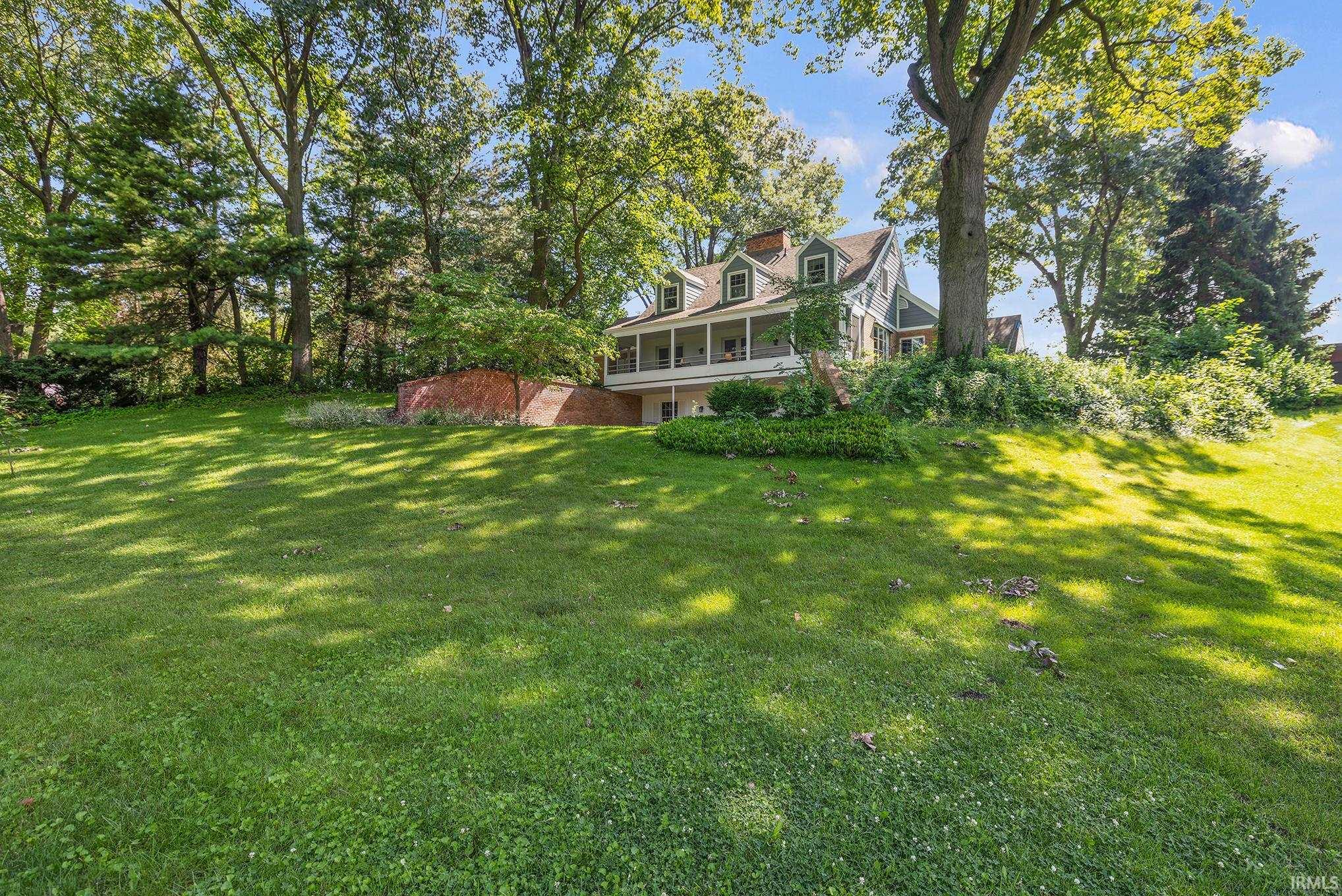 Spacious front lawn with a gentle slope and mature trees