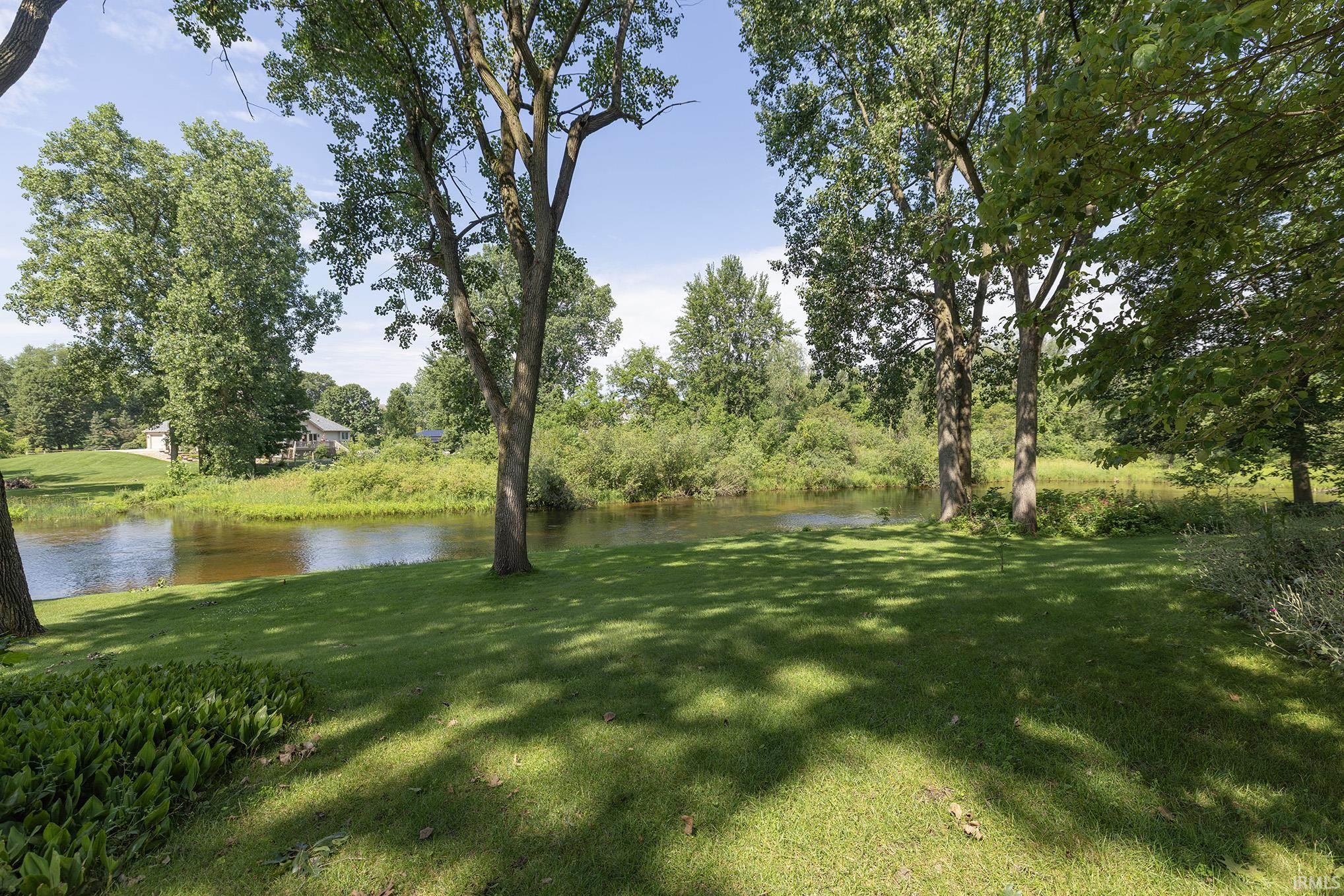 Expansive green lawn with mature trees and waterfront access