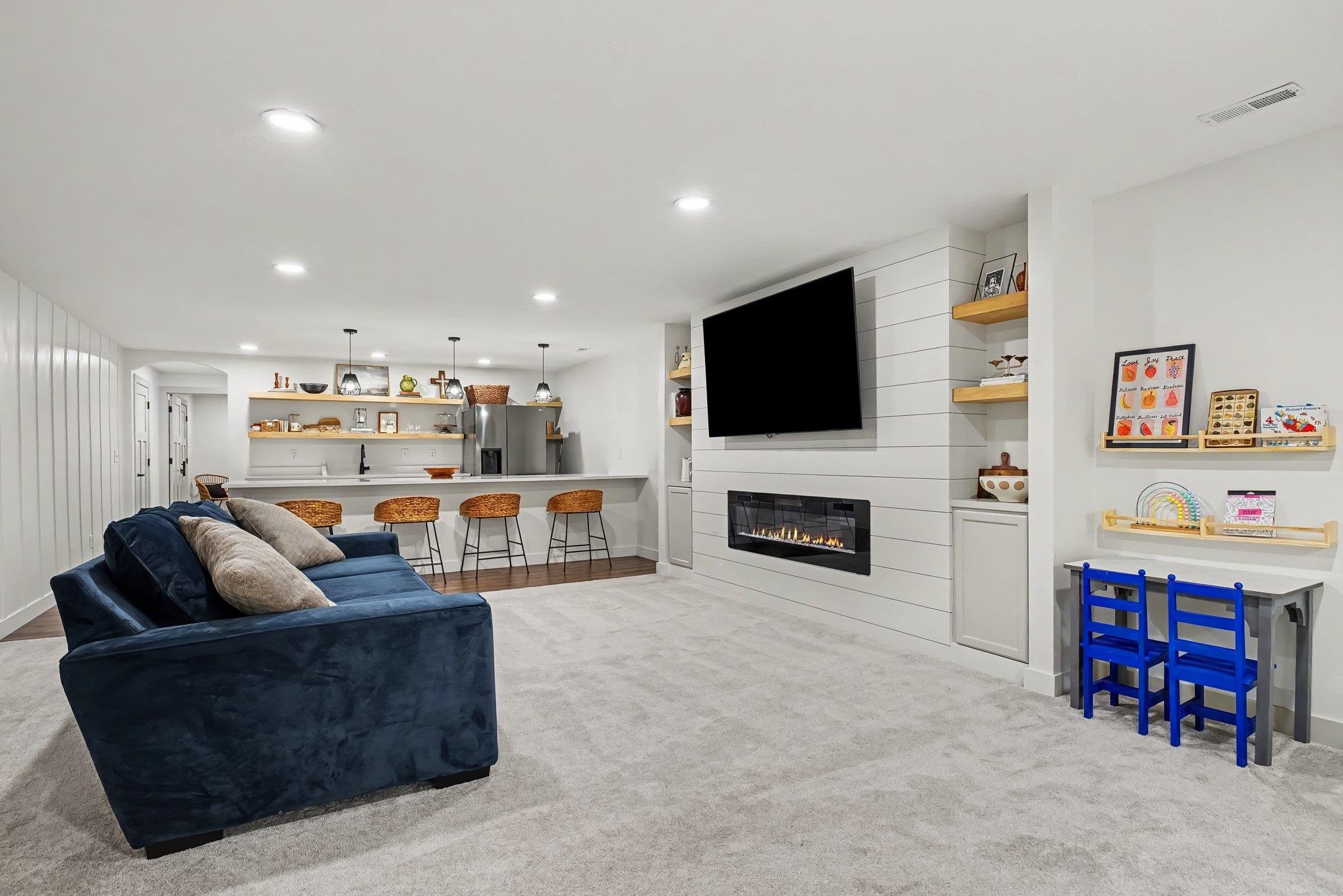 Spacious entertainment area featuring light-toned carpeting and recessed lighting