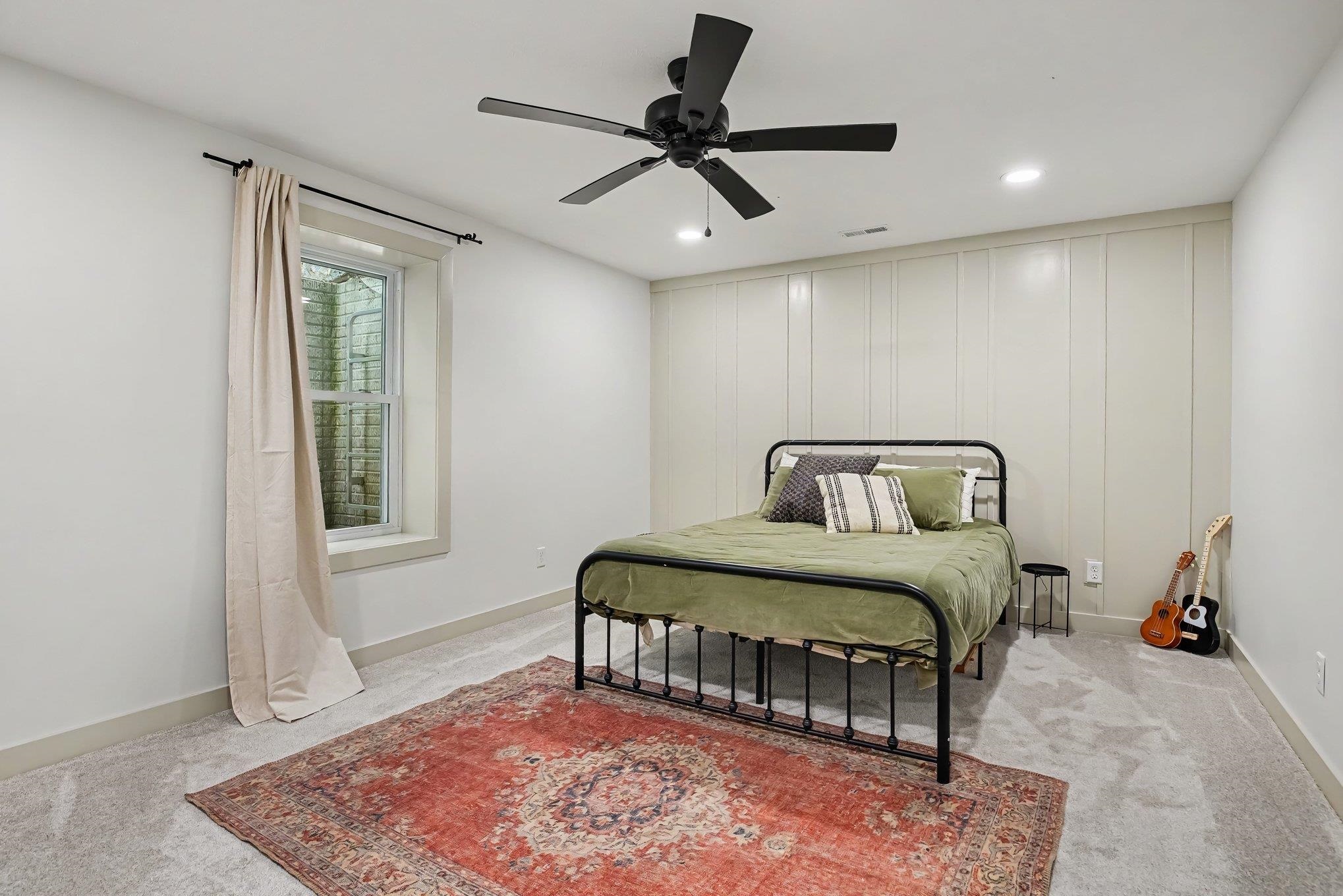 Bedroom featuring light gray carpeting, a window with trim, a board and batten accent wall, recessed lighting, and a ceiling fan