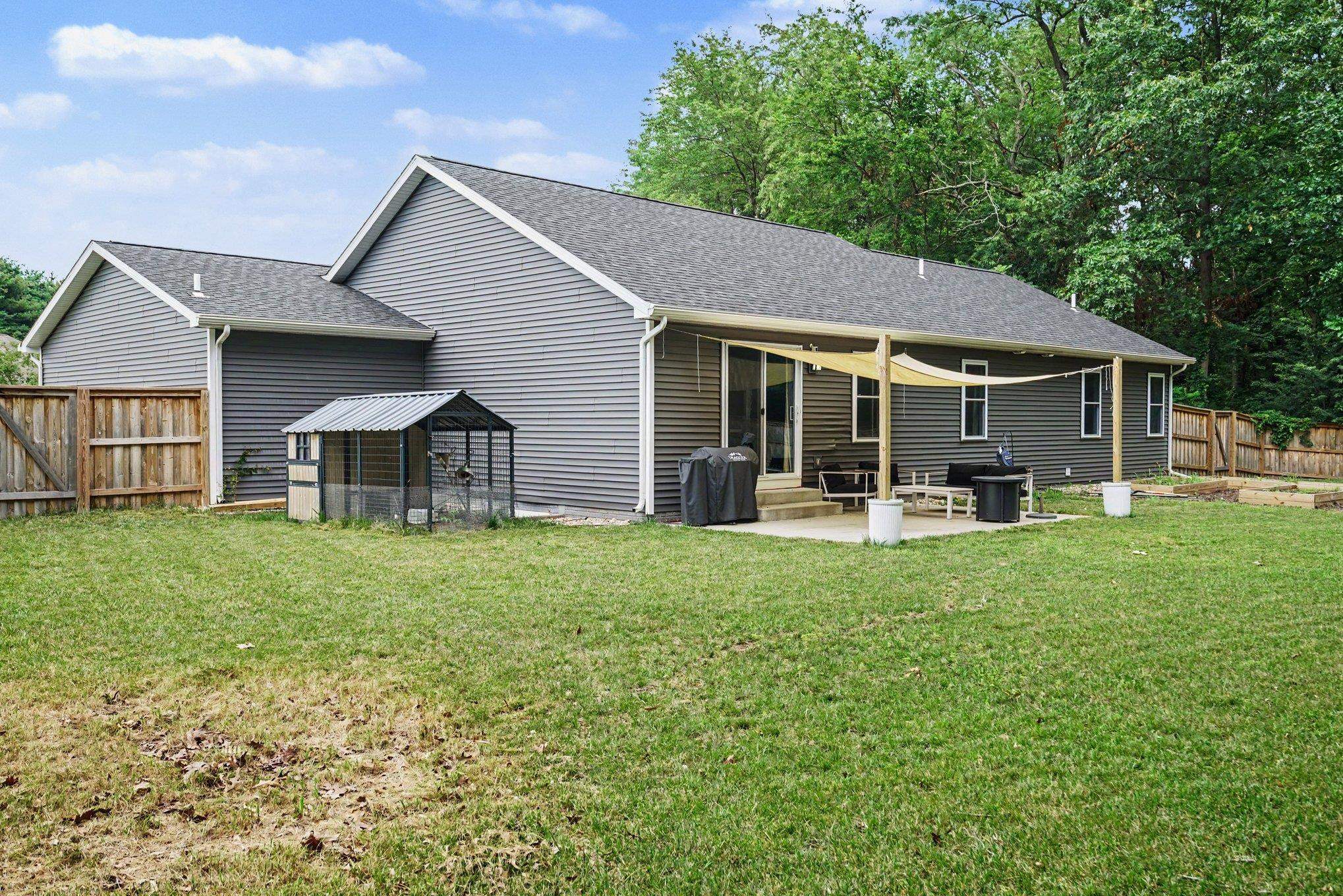 Rear exterior with gray horizontal siding, a dark shingled roof, and white trim