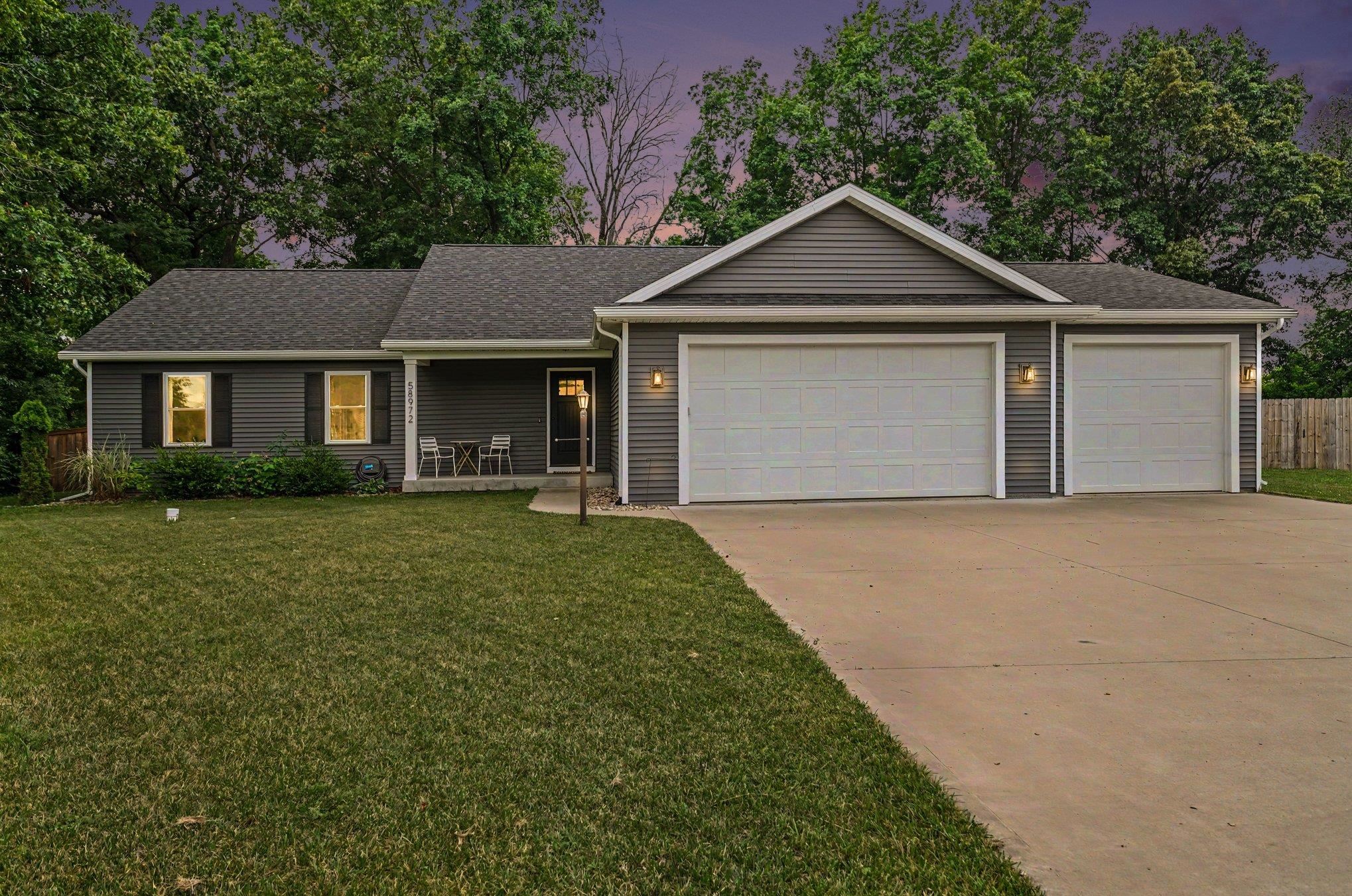 Ranch-style exterior featuring gray siding, a dark shingle roof, and a three-car garage
