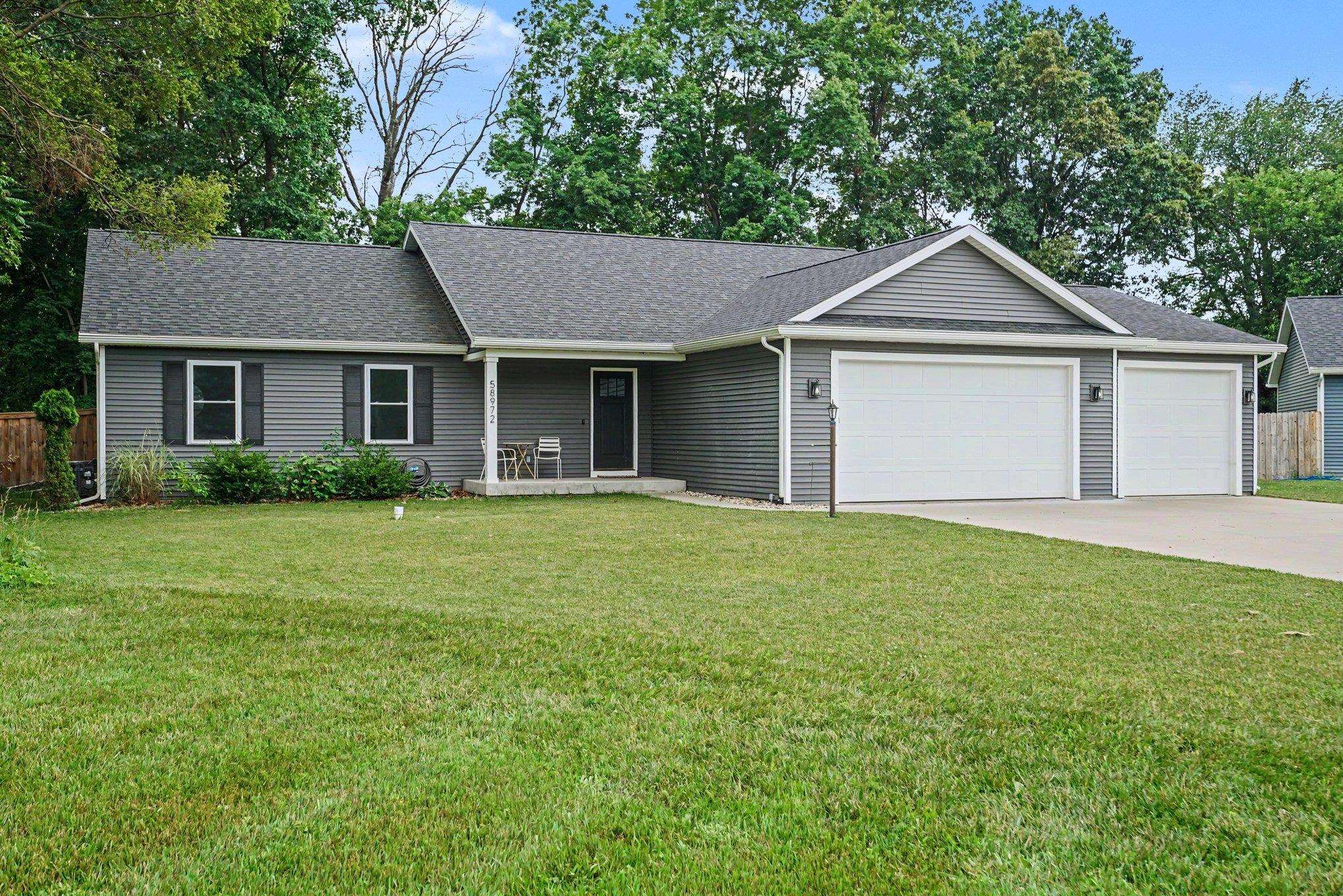 Ranch-style residence featuring gray horizontal siding, a covered front entry, and a multi-pitch roofline