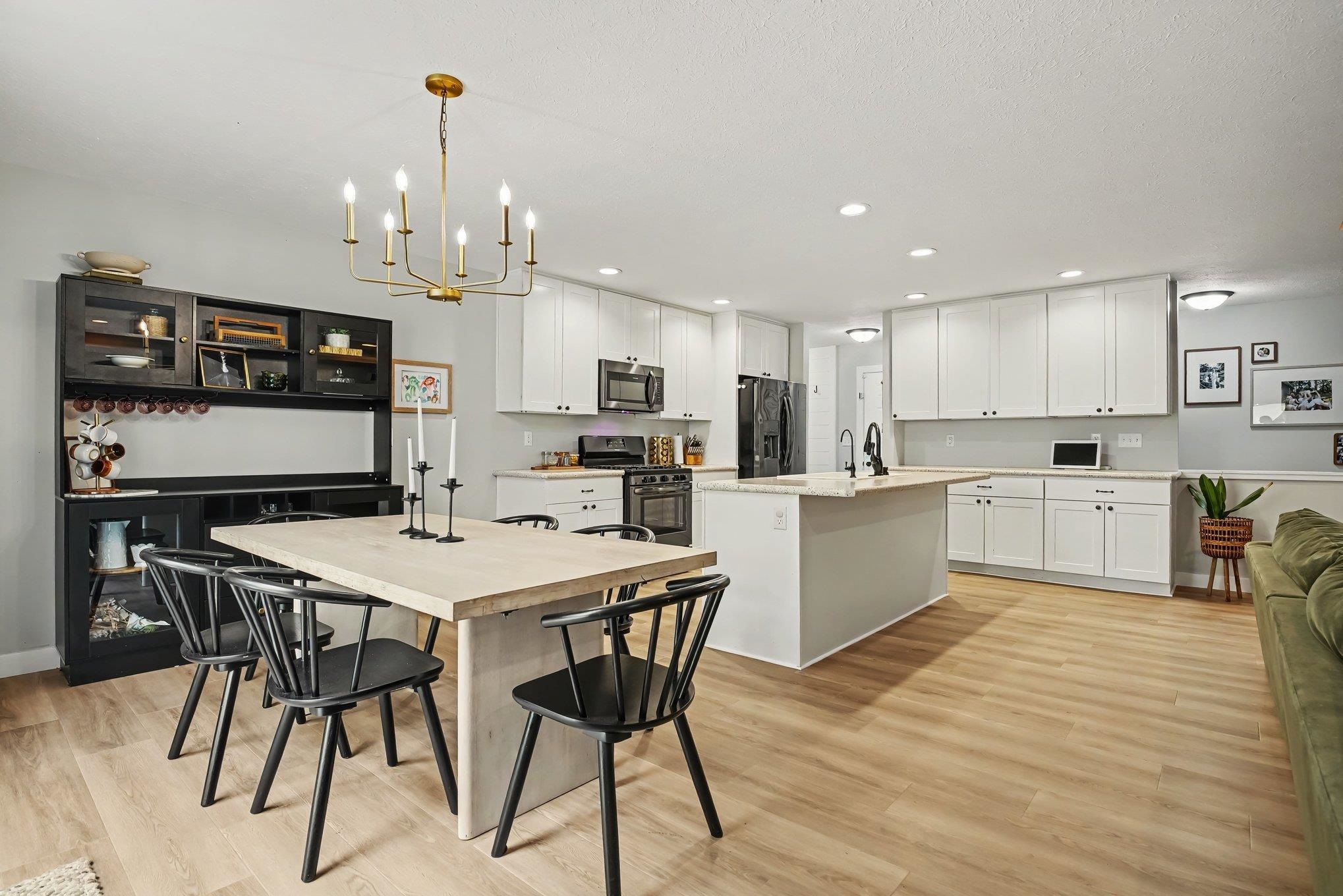 Open-concept living space featuring light wood-finish flooring, white cabinetry, and a central kitchen island with seating