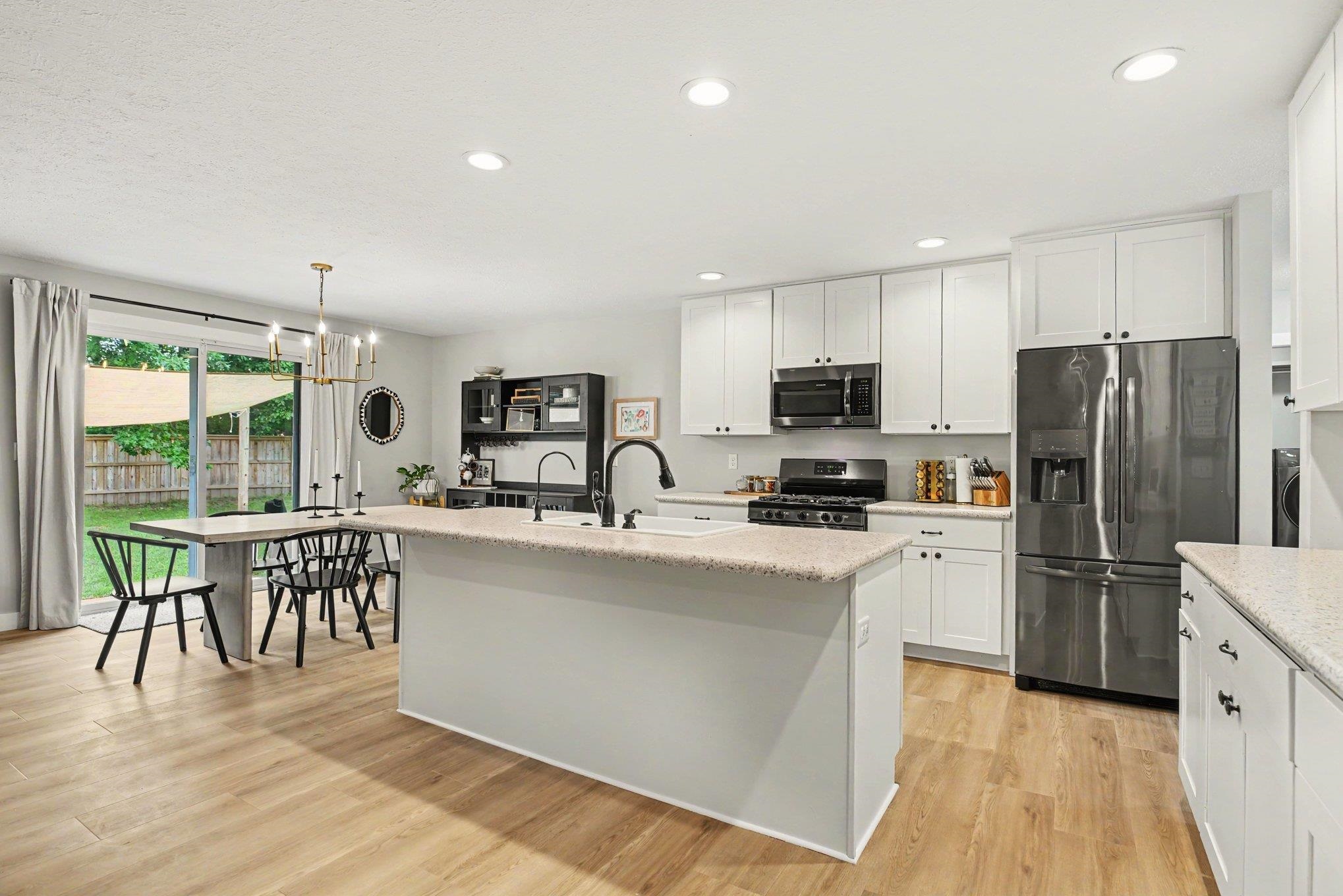 Modern kitchen featuring white cabinetry, light-toned countertops, and wood-finish flooring