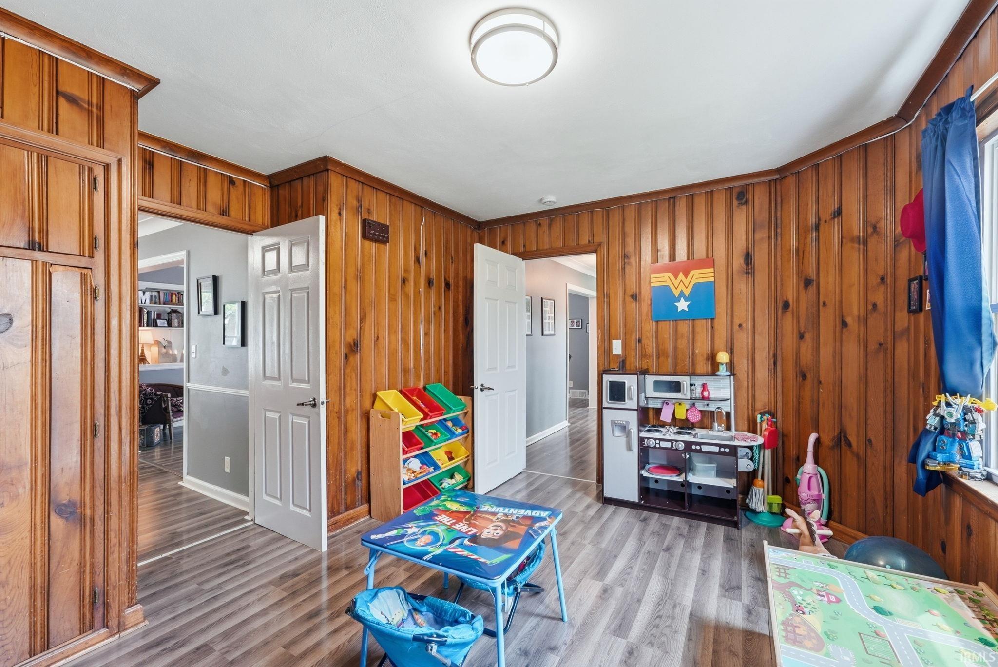 Charming family room featuring wood paneling, light wood-finish flooring.
