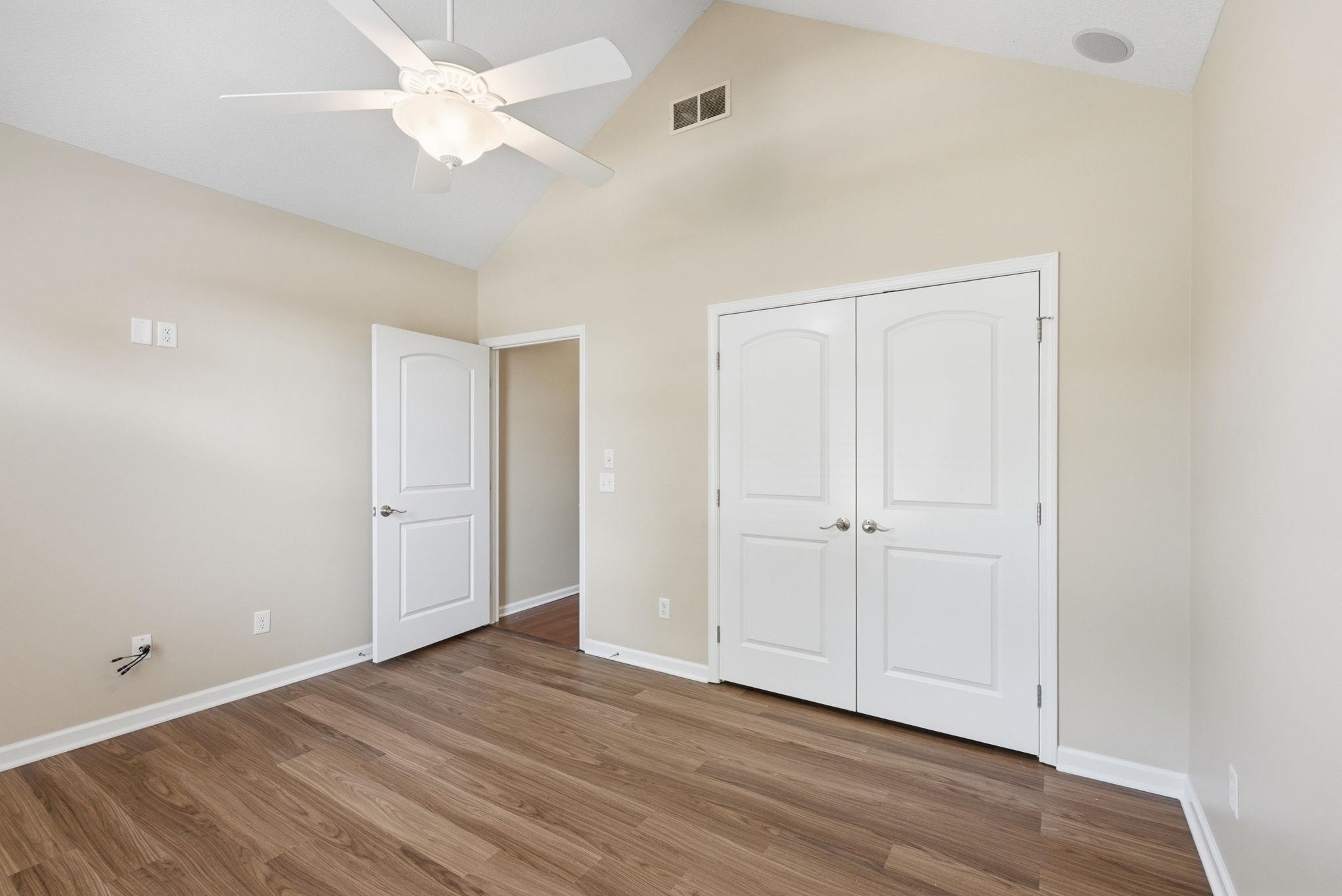 Spacious room featuring vaulted ceilings, wood-finish flooring, and neutral wall tones