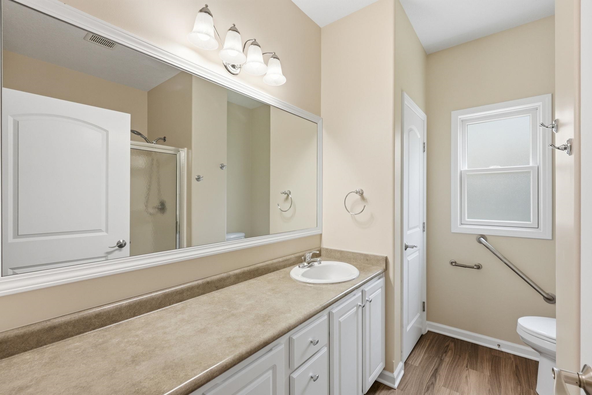 Bathroom featuring a long vanity with an integrated sink, white cabinetry, and a neutral-toned countertop