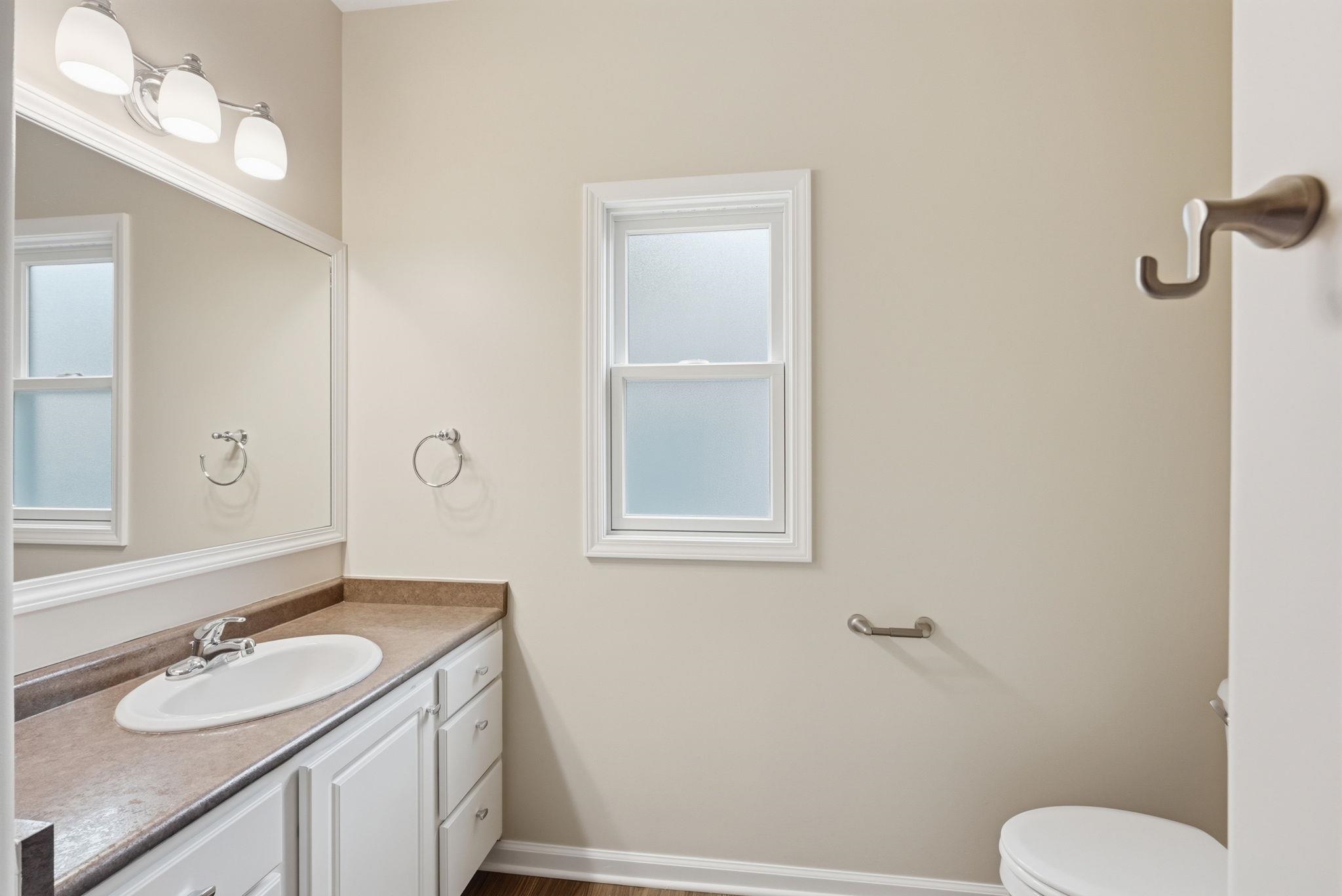 Bathroom vanity with a white rectangular sink, a light brown countertop, and white cabinetry