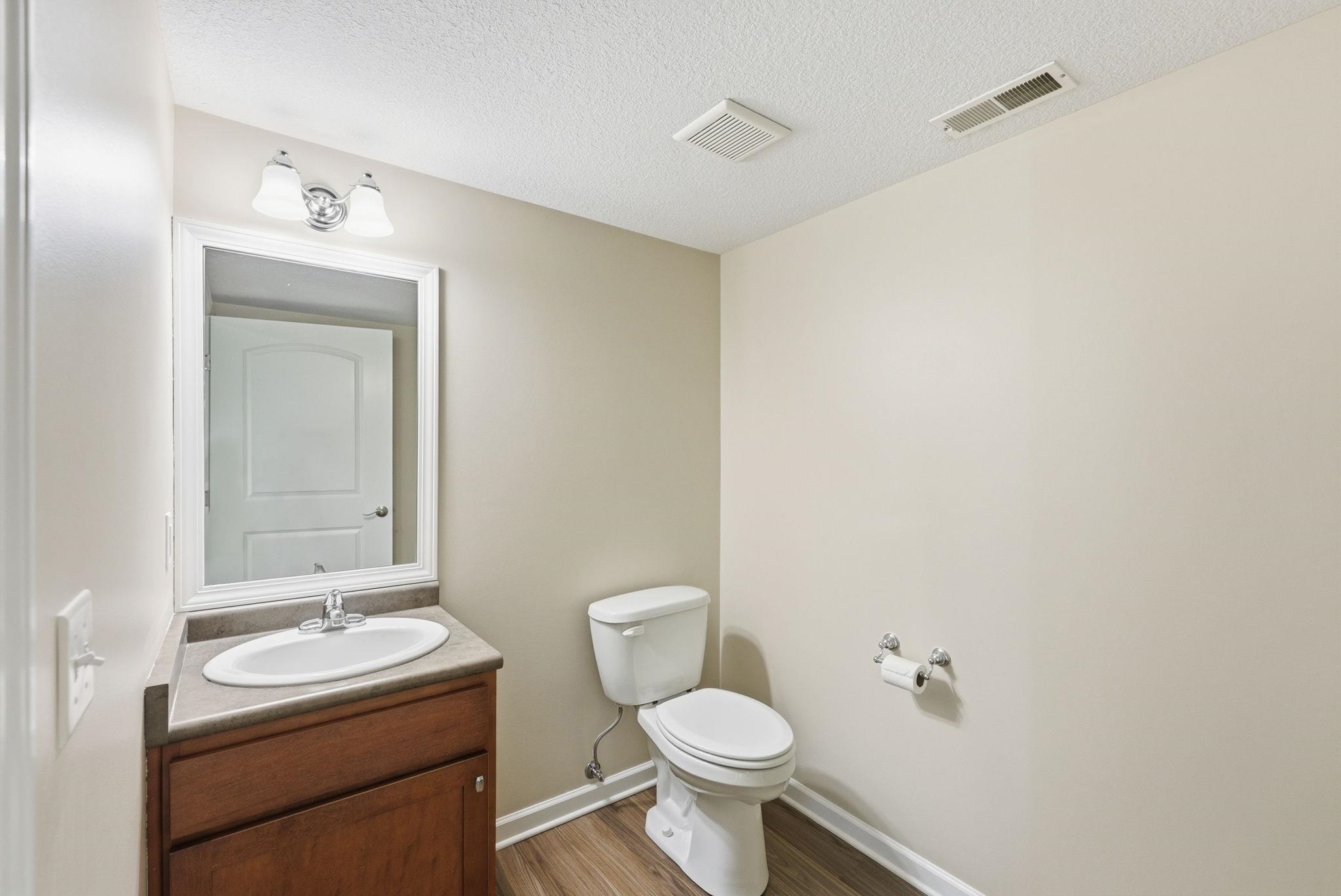 Bathroom vanity featuring a white oval sink, chrome faucet, and a wood-finish cabinet