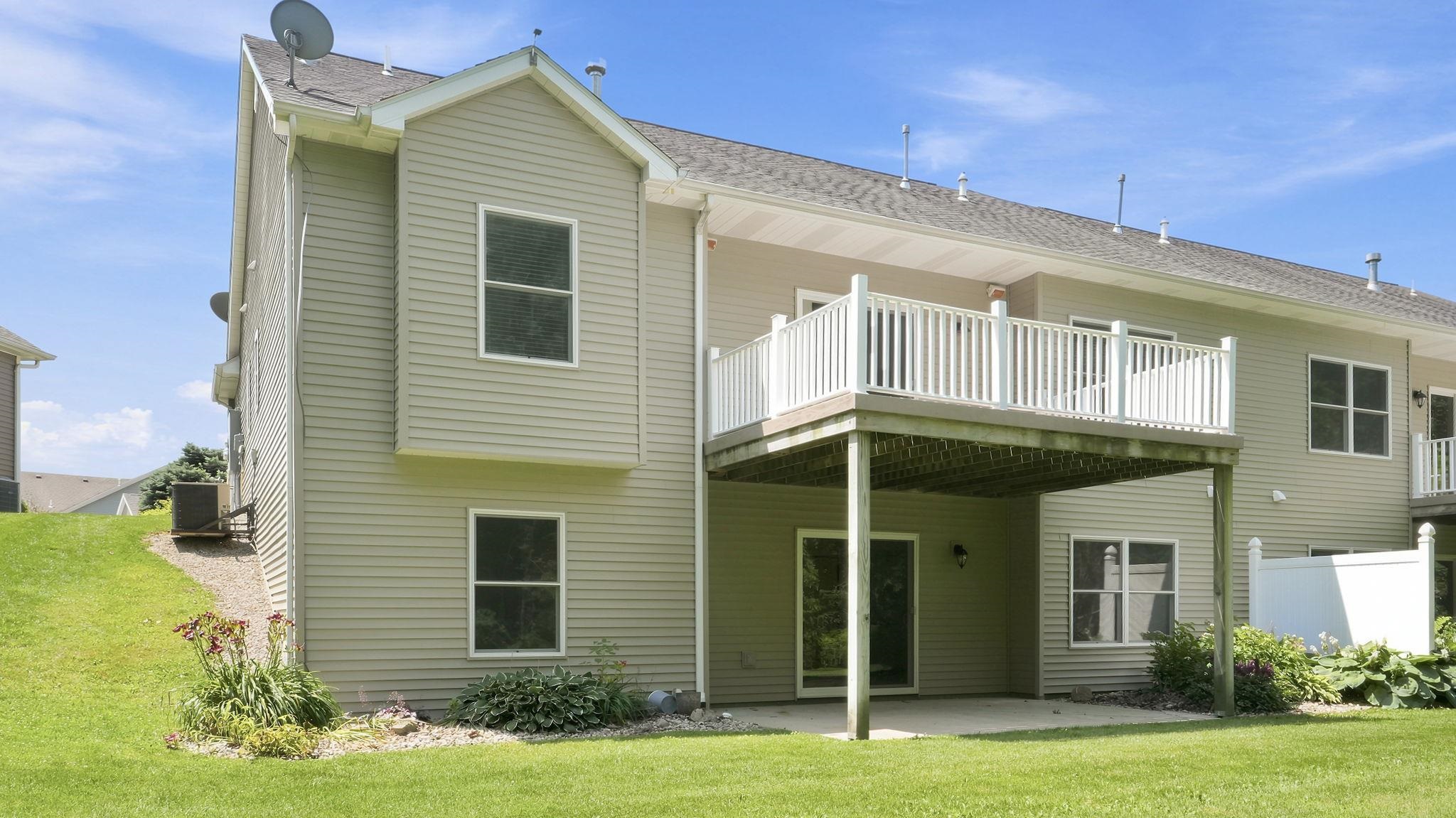 Rear exterior featuring a raised deck with white railing, a ground-level patio, and light-colored siding