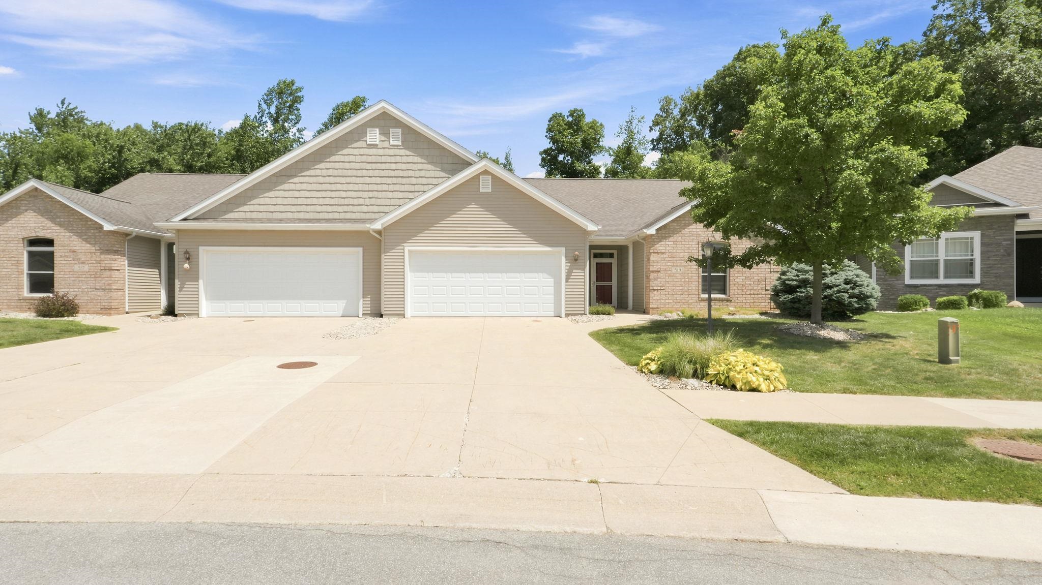 Exterior featuring a split garage, brick facade, and tan siding