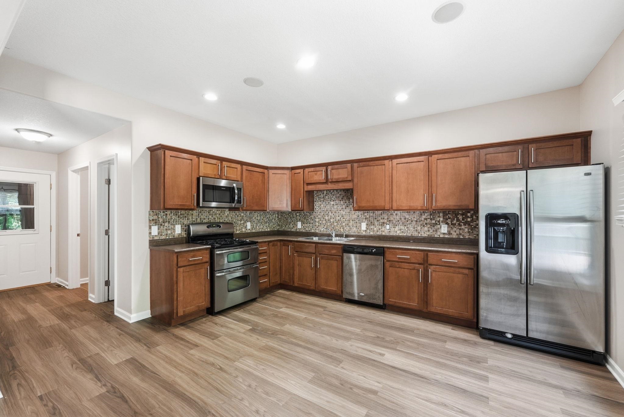 Kitchen featuring wood-finish flooring, recessed lighting, and stainless steel appliances including a double-oven range, microwave, dishwasher, and refrigerator