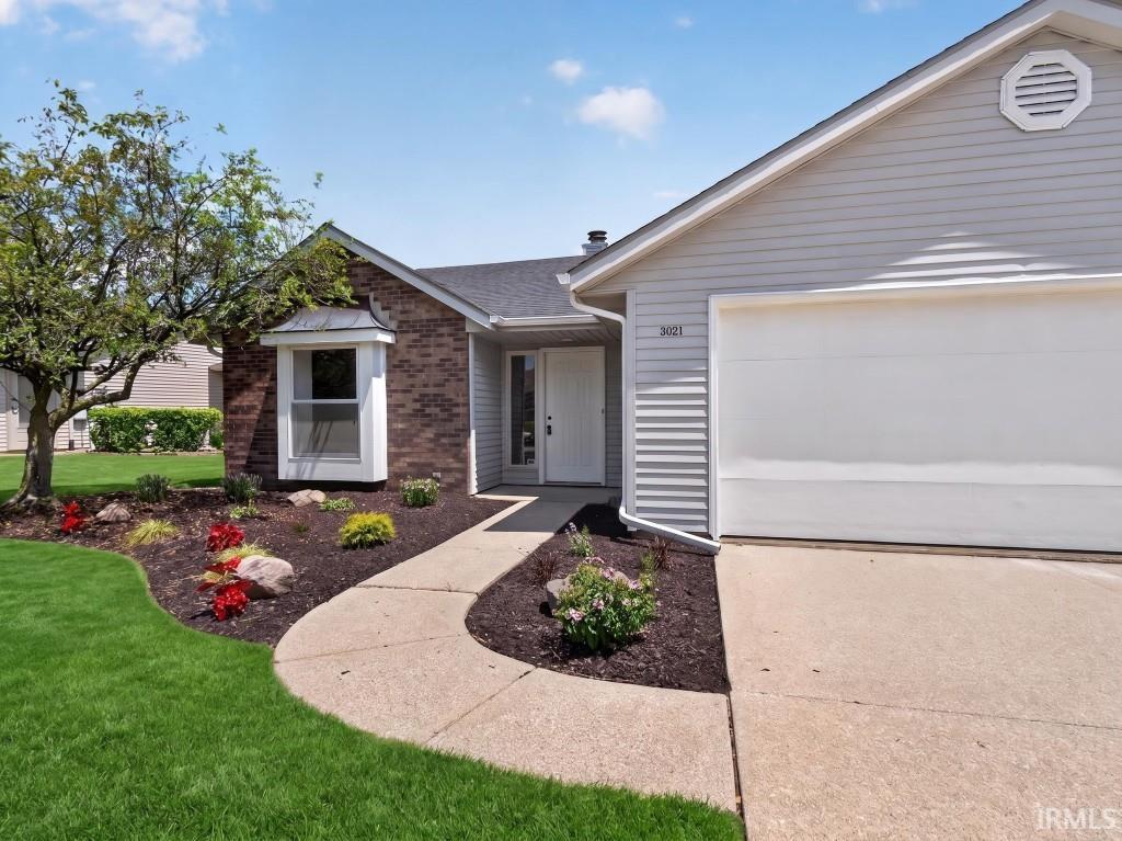 Brick and siding exterior featuring a bay window, concrete walkway, and attached garage