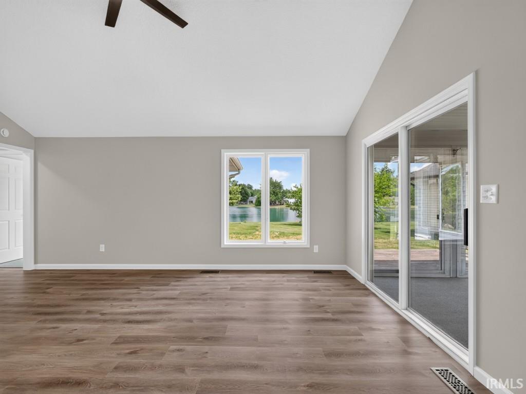 Spacious room with wood-finish flooring, neutral wall tones, and a vaulted ceiling with a ceiling fan