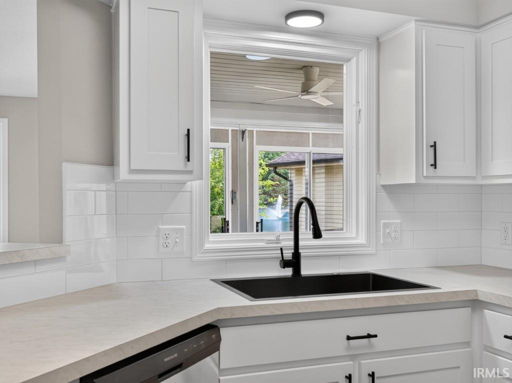 Kitchen featuring white shaker cabinetry, light-toned countertops, a black single-basin sink with a matte black gooseneck faucet, and a white subway tile backsplash