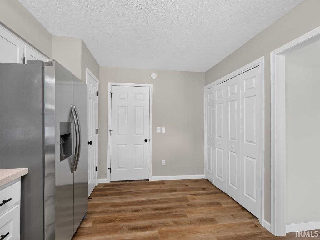 Stainless steel refrigerator and wood-finish flooring complement the light-toned walls