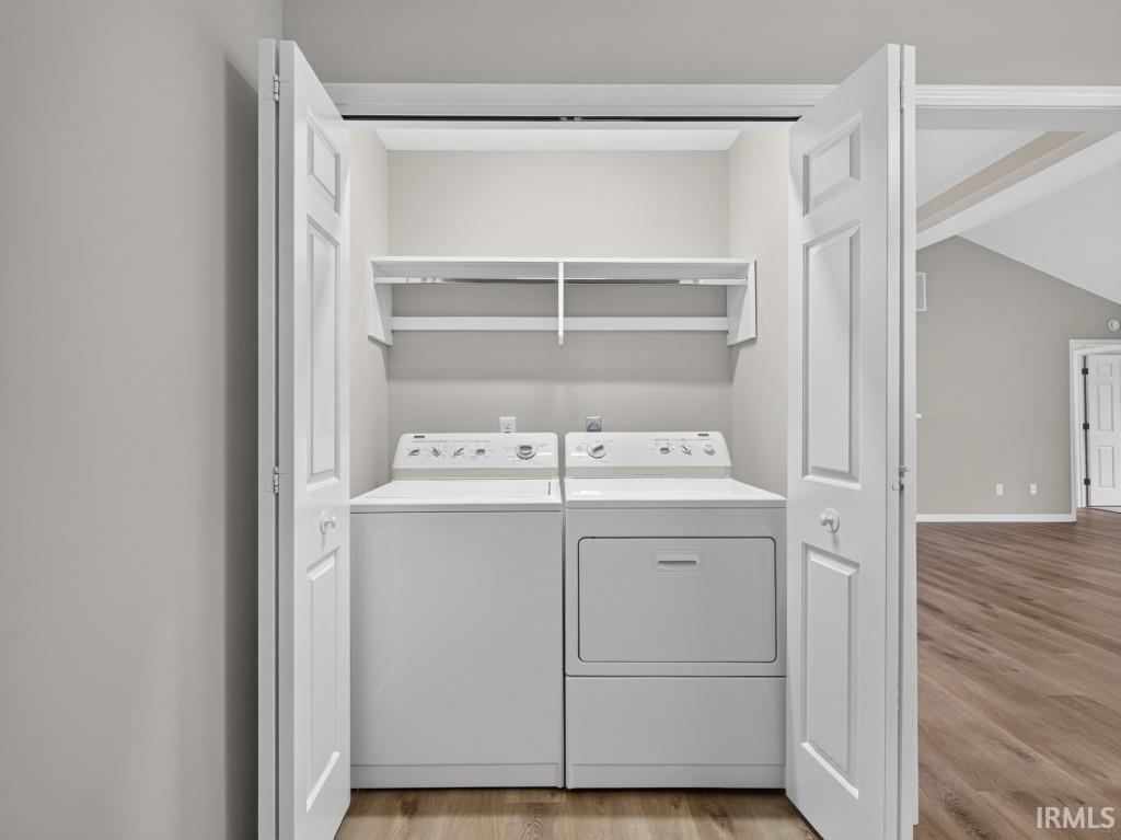 Laundry closet featuring bi-fold doors, white shelving, and wood-finish flooring
