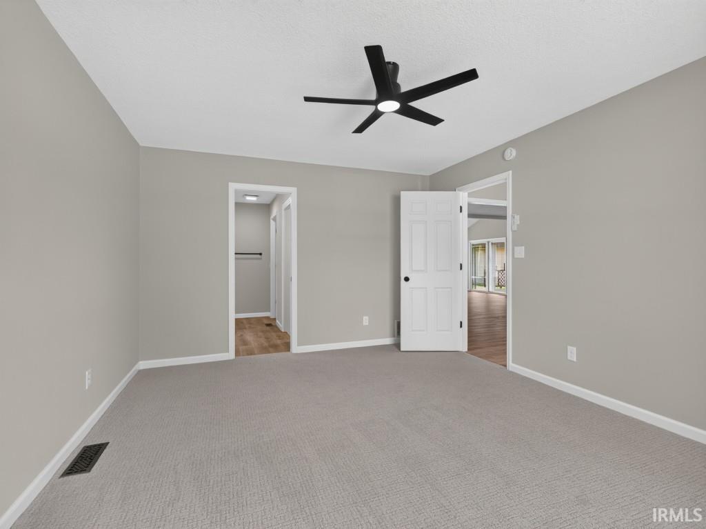 Spacious room with light gray walls, textured ceiling, and gray carpeting