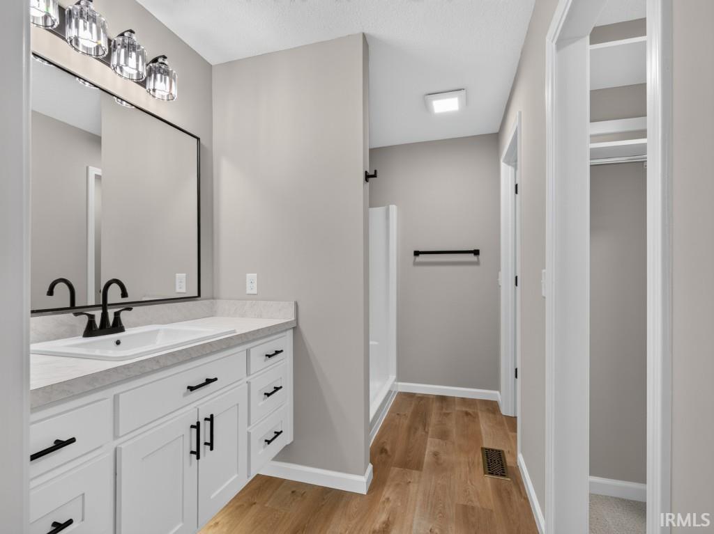 Modern bathroom vanity featuring white cabinetry, matte black hardware, a rectangular sink, and a light-toned countertop