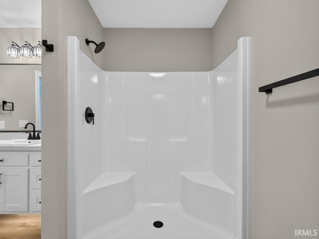 White shower stall with built-in seating, matte black shower head, and coordinating faucet