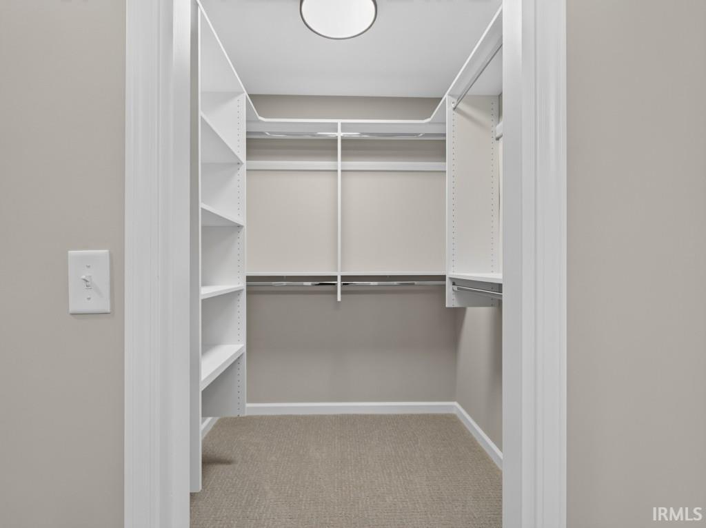Walk-in closet featuring white shelving, multiple hanging rods, and recessed ceiling lighting