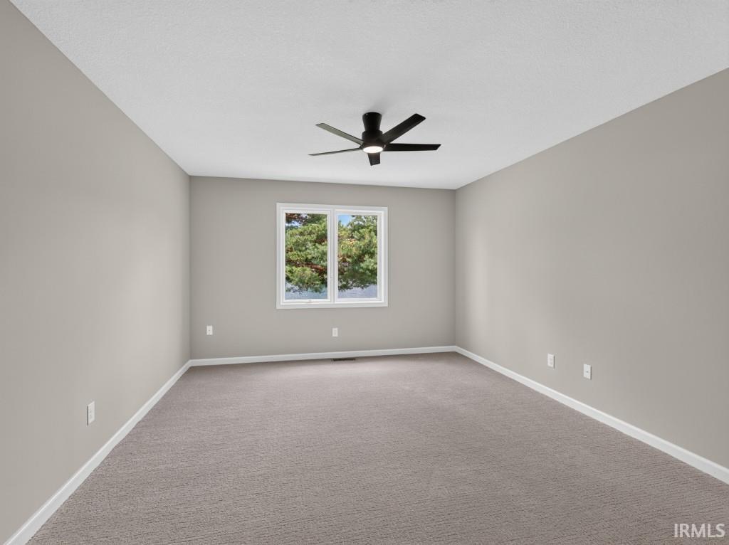 Spacious room featuring neutral carpeting, light gray wall paint, and white trim