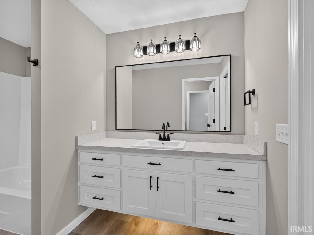 Bathroom featuring a floating white vanity with ample storage, a white countertop, and a rectangular undermount sink with a matte black faucet
