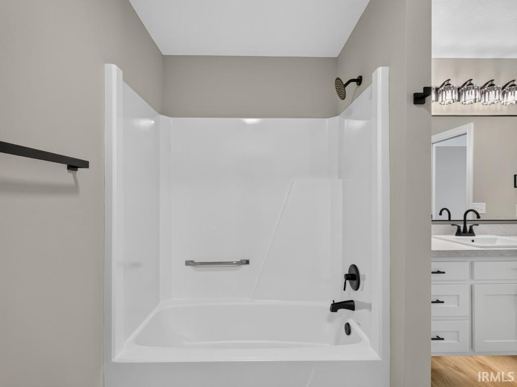White tub and shower combination with black fixtures, including a showerhead and faucet