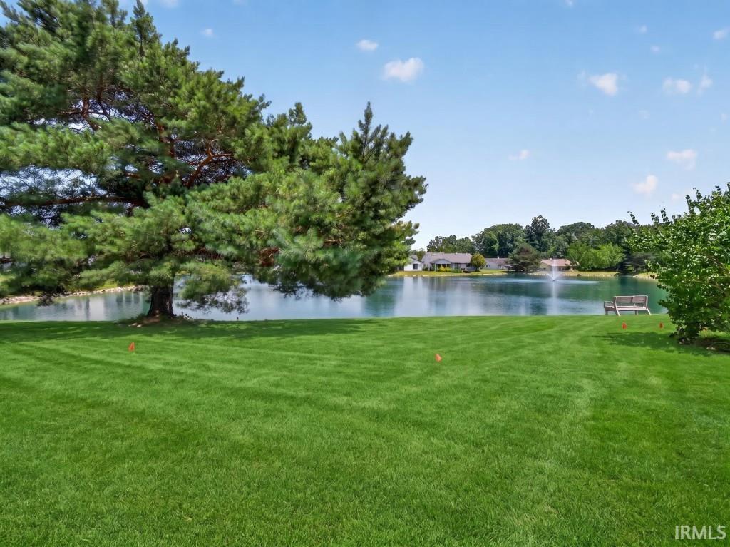 Expansive green lawn bordering a tranquil pond with a decorative fountain