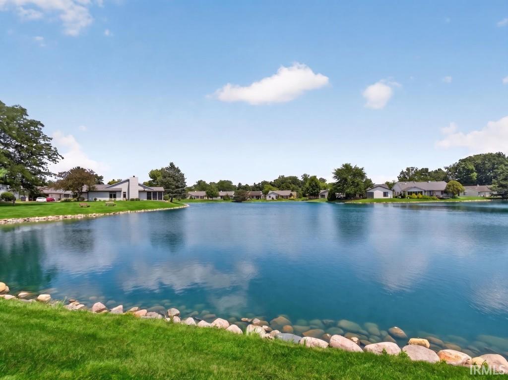 Expansive waterfront property featuring a manicured lawn, natural stone edging along the water, and mature trees