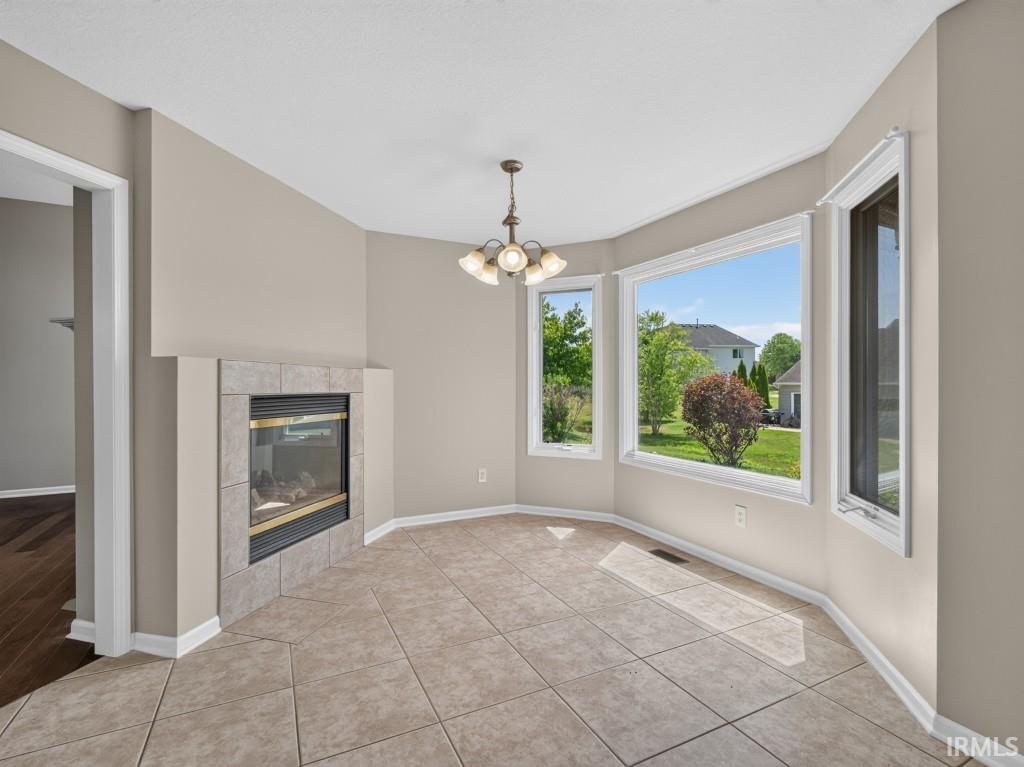 Dining area featuring a tiled fireplace with a glass front, bay windows, ceramic tile flooring, and a ceiling-mounted light fixture