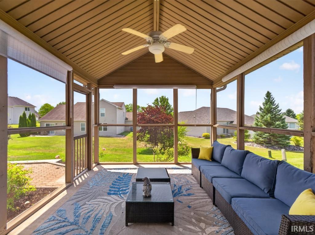 Screened porch featuring a vaulted ceiling with exposed beams, an overhead ceiling fan, and multiple exterior openings
