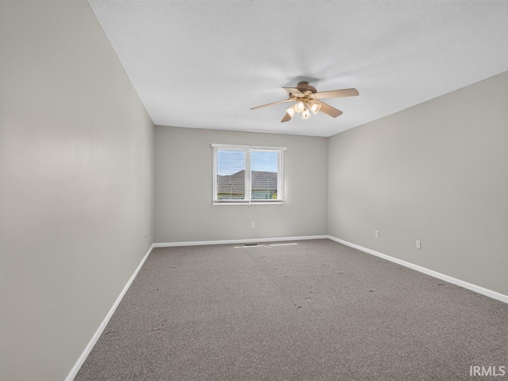 Spacious room featuring neutral carpeting, light gray wall paint, and white trim