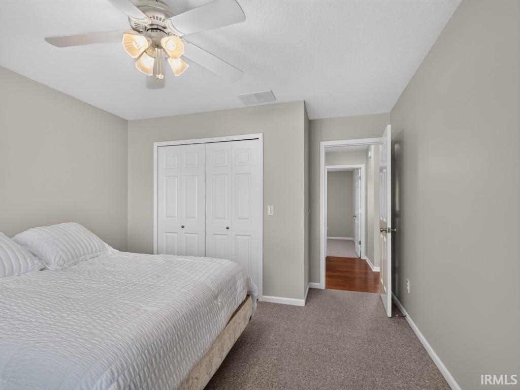 Carpeted room with a ceiling fan featuring a light kit and neutral wall tones