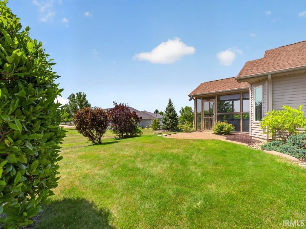 Expansive rear lawn featuring a screened porch, an outdoor patio, and mature landscaping