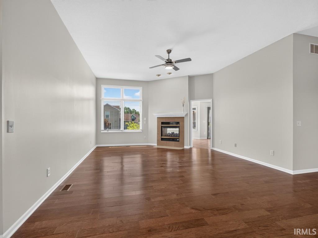 Spacious living area featuring wood-finish flooring, a built-in fireplace with a hearth, and a contemporary ceiling fan