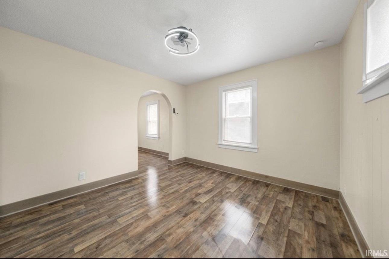 Spacious room featuring wood-finish flooring, light-colored walls, and a modern ceiling fan with integrated lighting