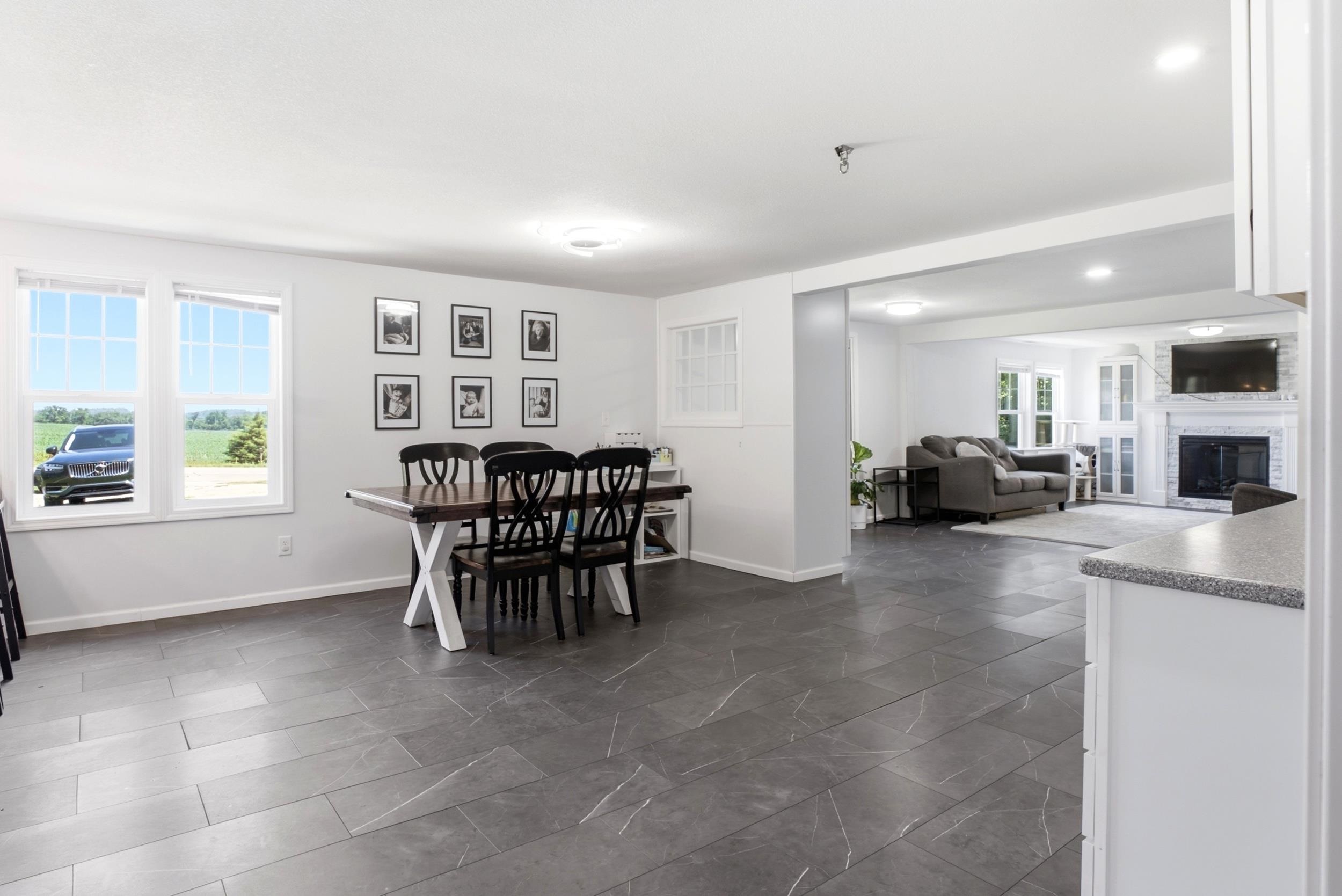 Open-concept dining area featuring large windows, dark grey tile flooring, and recessed lighting
