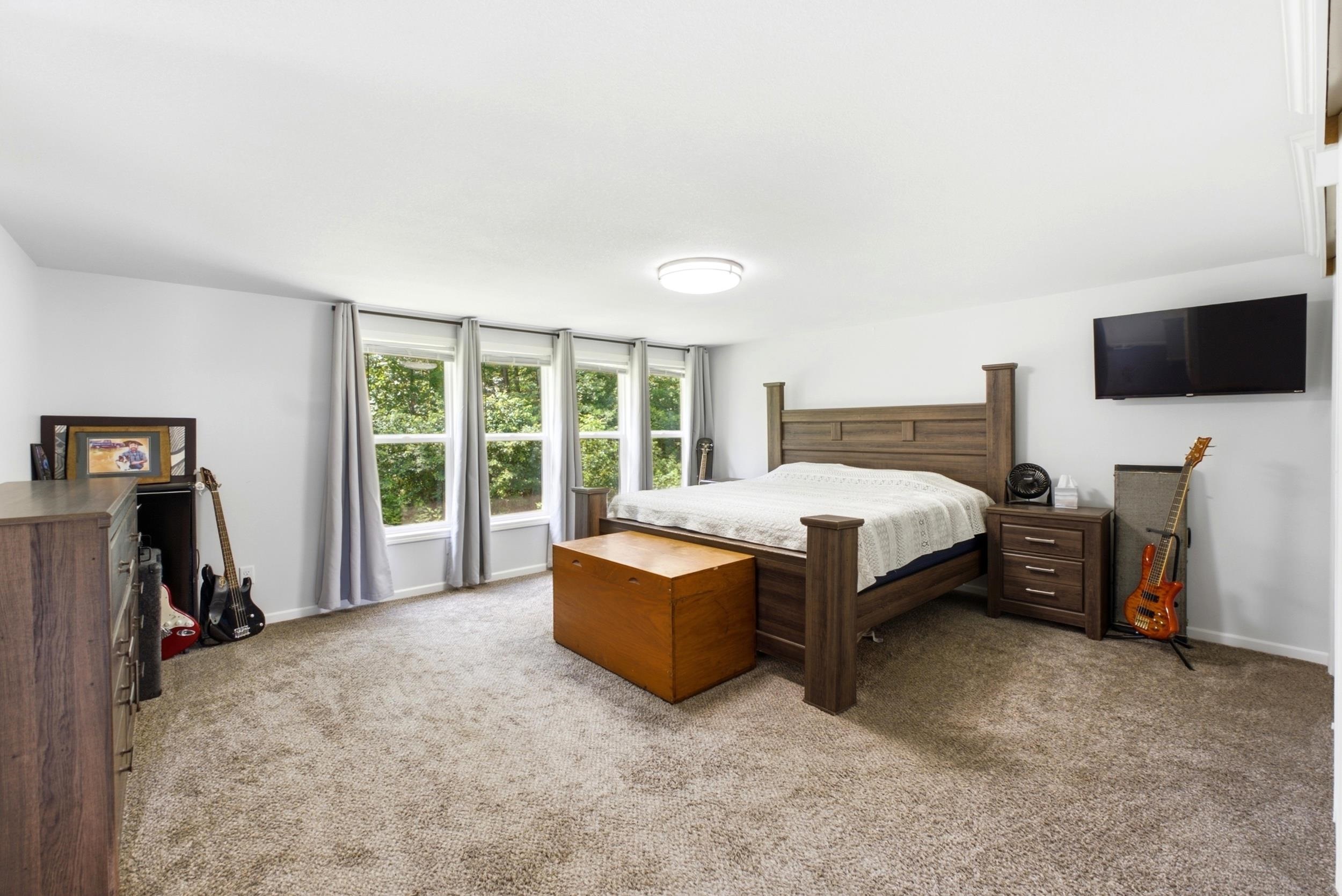 Spacious room featuring multiple windows, neutral wall tones, textured carpeting, and a flush-mount ceiling light