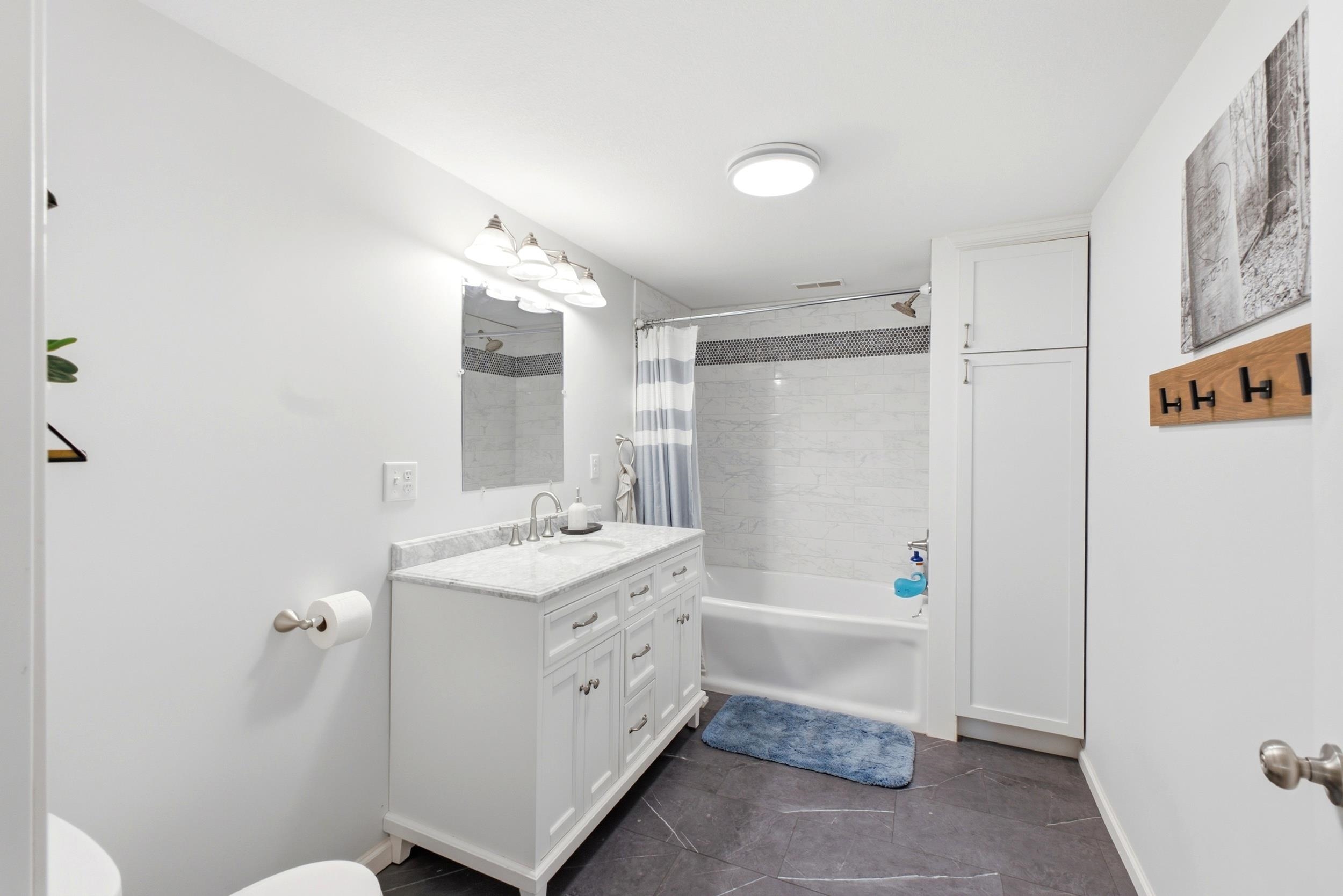 White vanity with a light-toned countertop, set against a backdrop of white walls