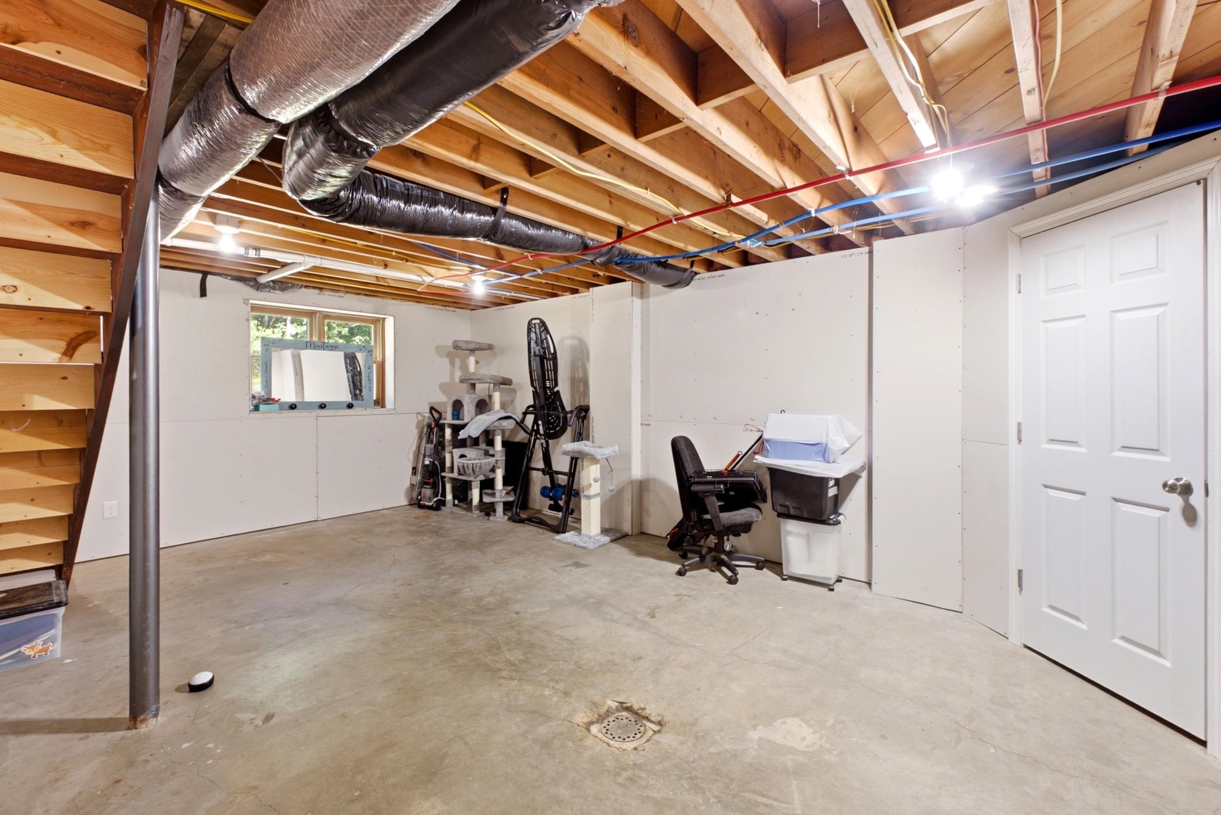 Unfinished basement with exposed ceiling joists, concrete flooring, and a single window