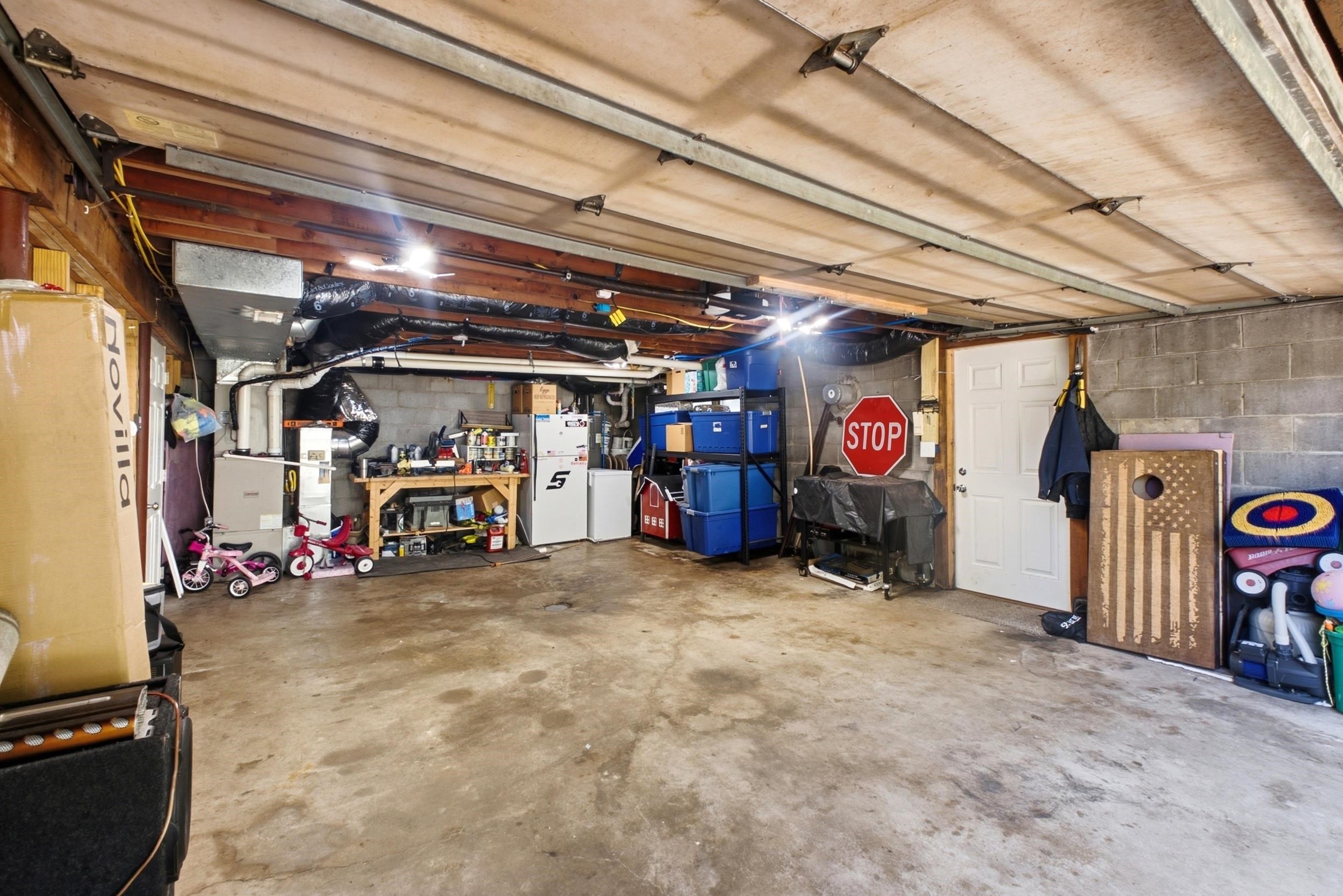 Spacious garage featuring concrete flooring, exposed wood beam ceiling, block wall construction, and a white entry door