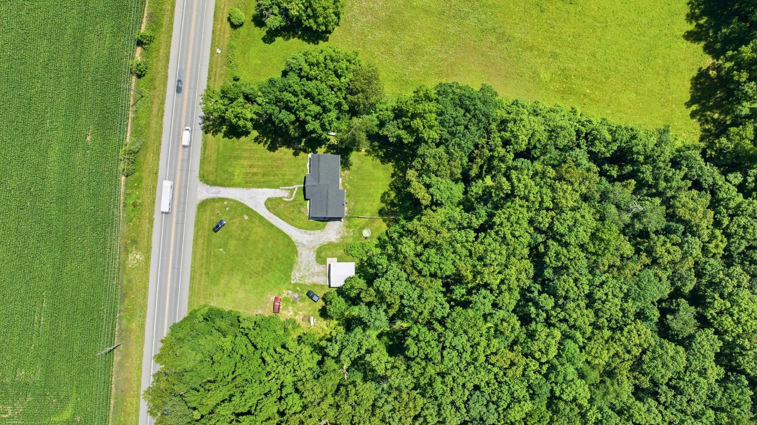 Aerial perspective showcasing a property with a gabled roofline, surrounded by dense natural tree lines