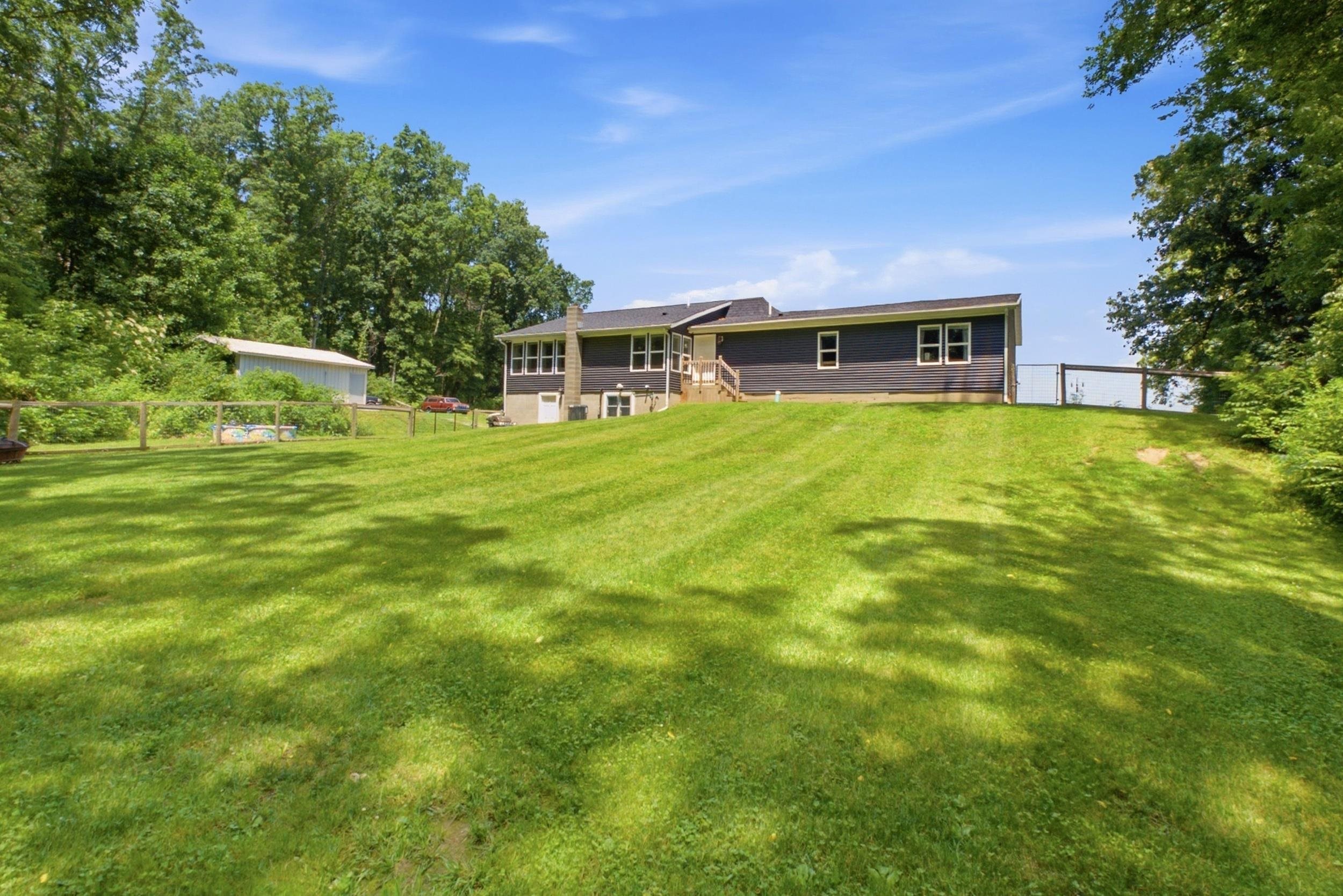 Spacious backyard featuring a sloped lawn and mature trees