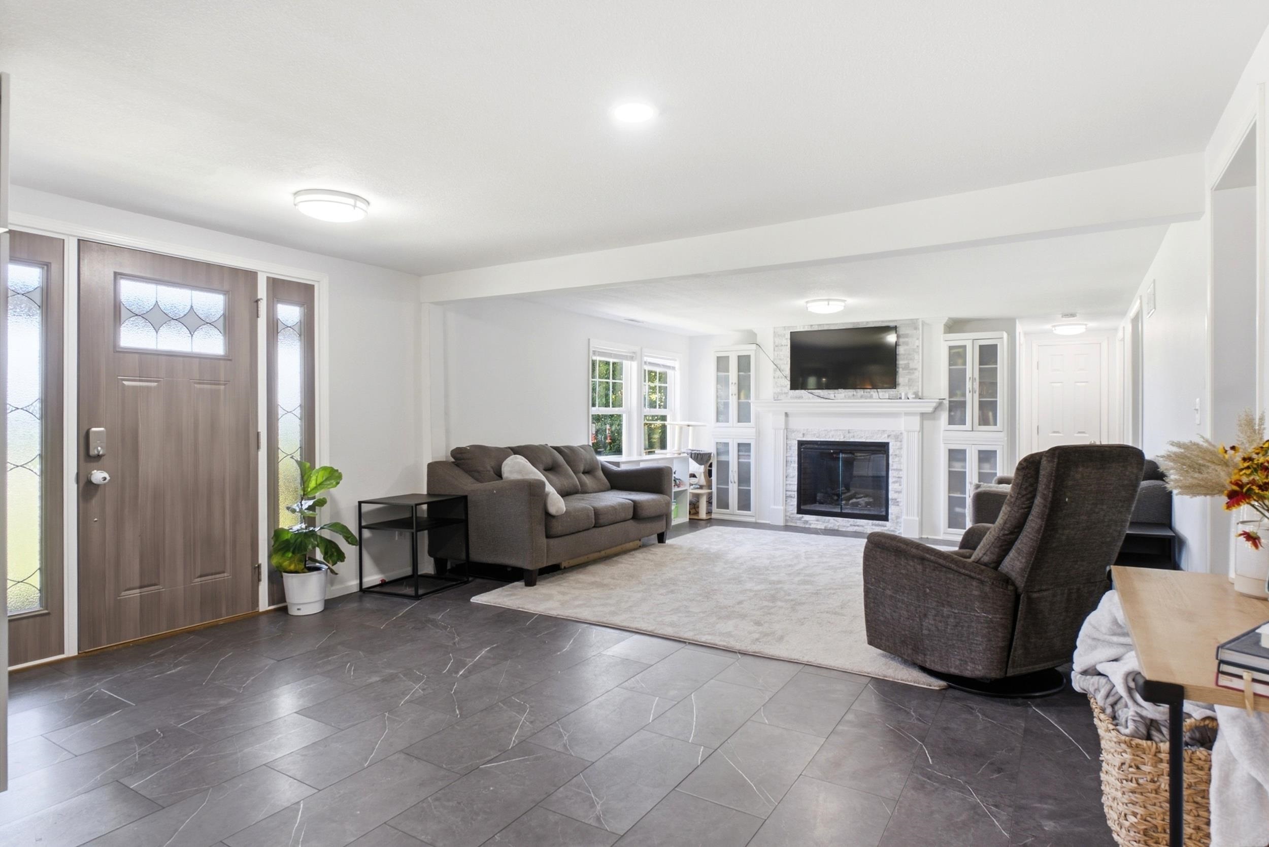 Entry foyer with slate-style tile flooring and a wood-finish entry door with decorative glass sidelights