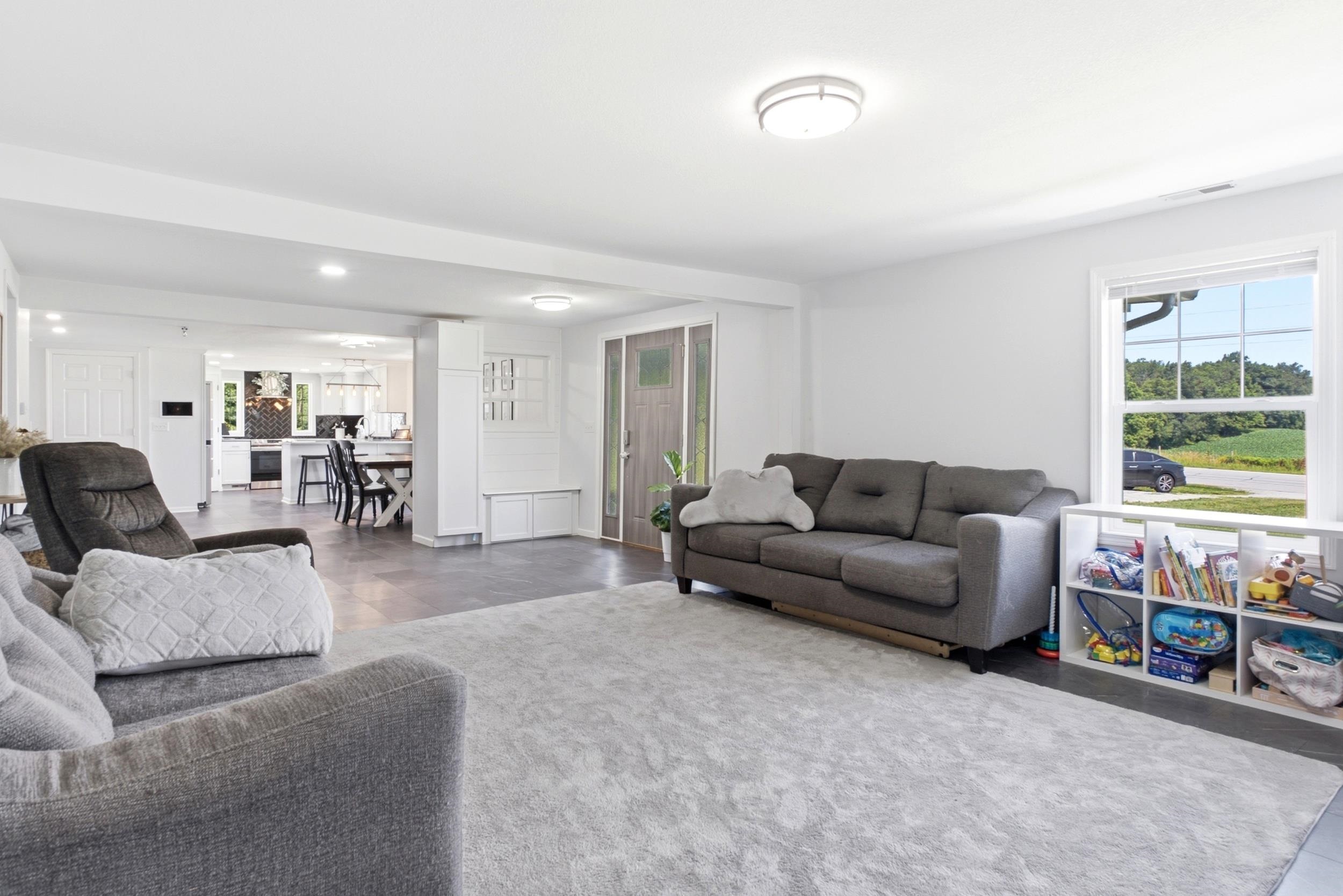 Spacious open-concept living area featuring light gray walls, recessed lighting, and dark-toned flooring
