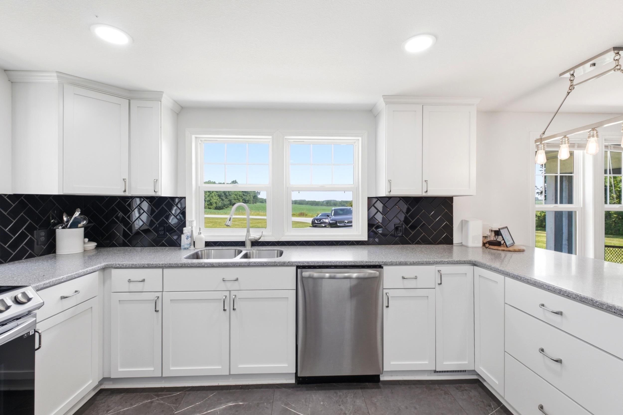 U-shaped kitchen featuring white shaker cabinetry, speckled countertops, and a black herringbone tile backsplash